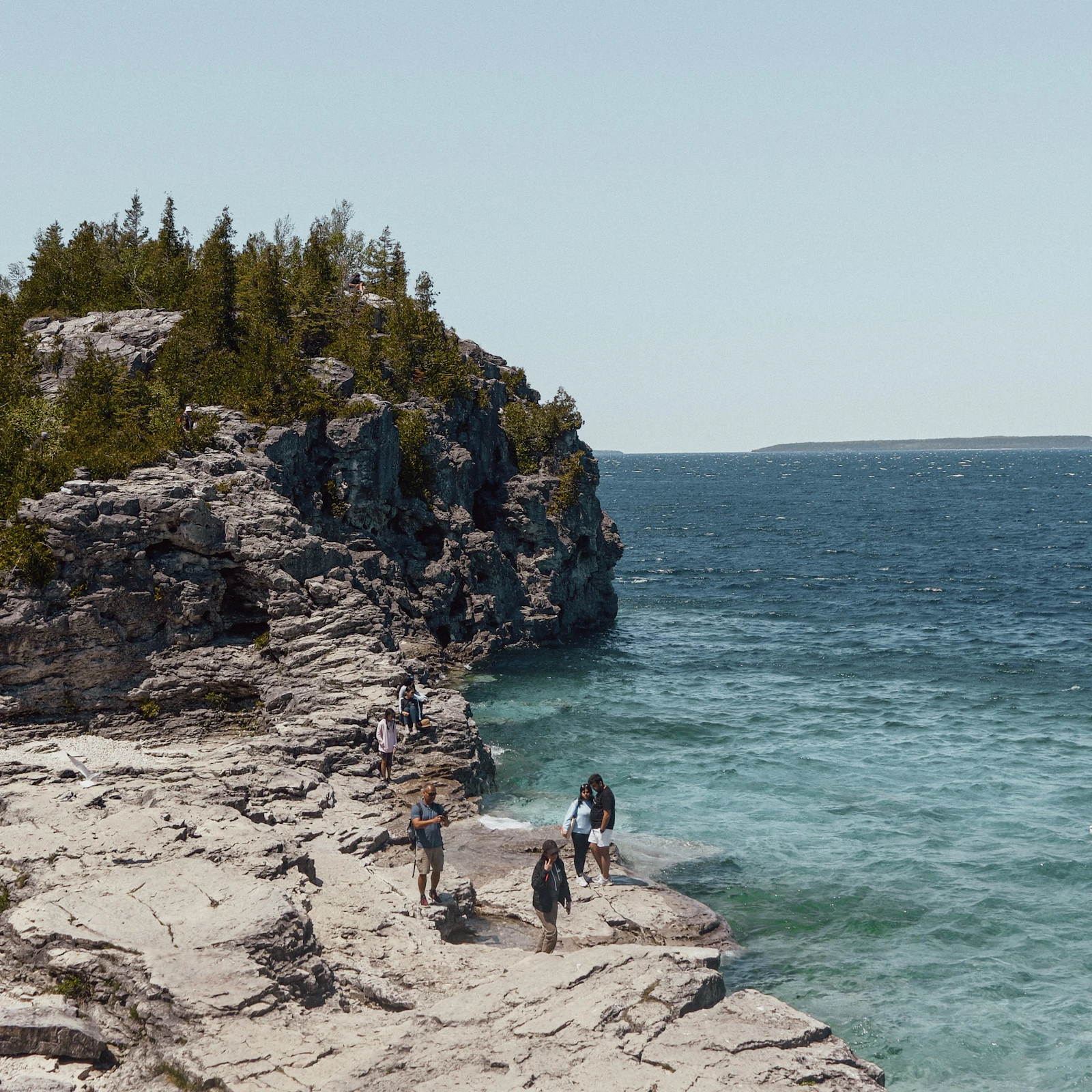 People hiking along the rocky shoreline at Bruce Peninsula Grotto