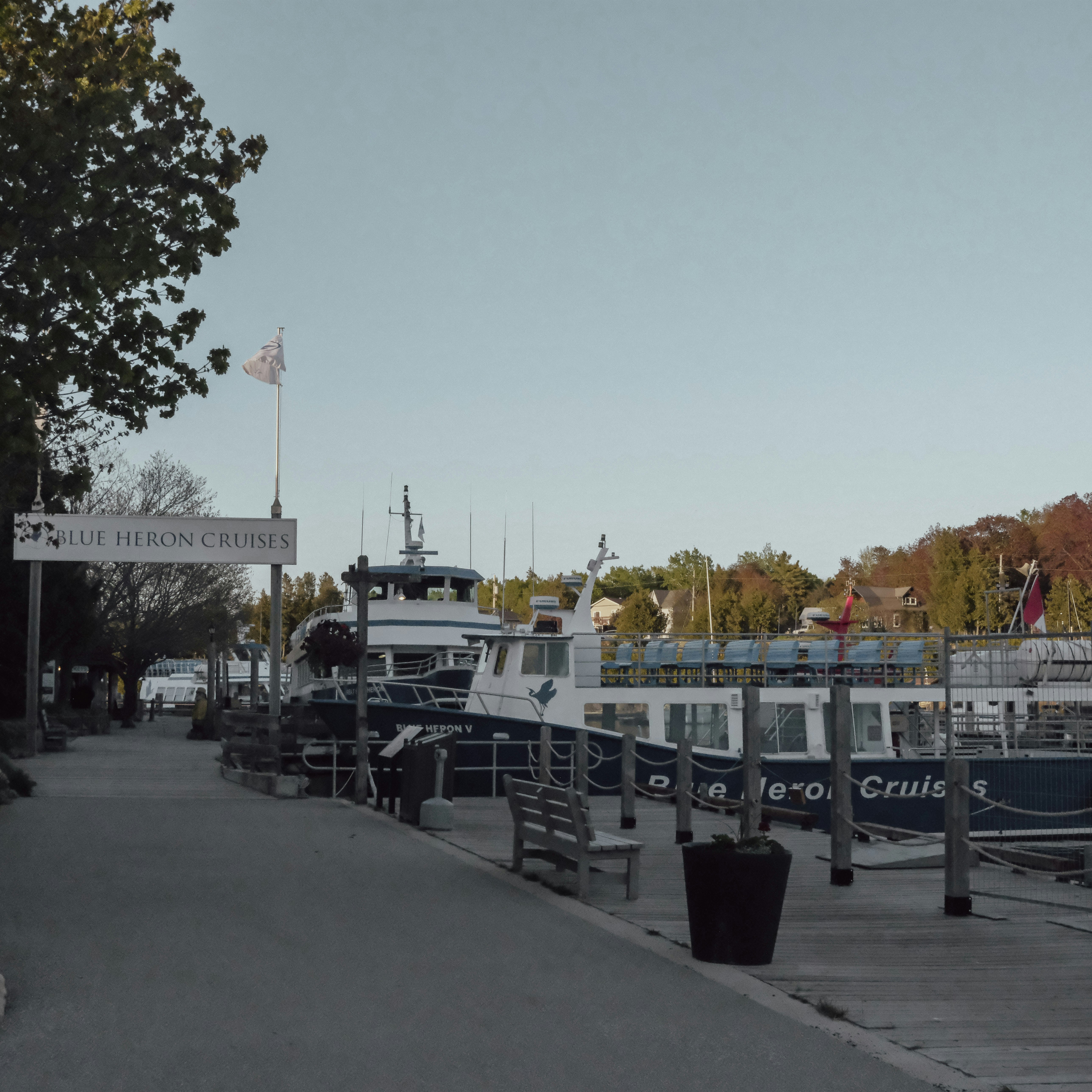 Boats docked along a scenic waterfront with trees.