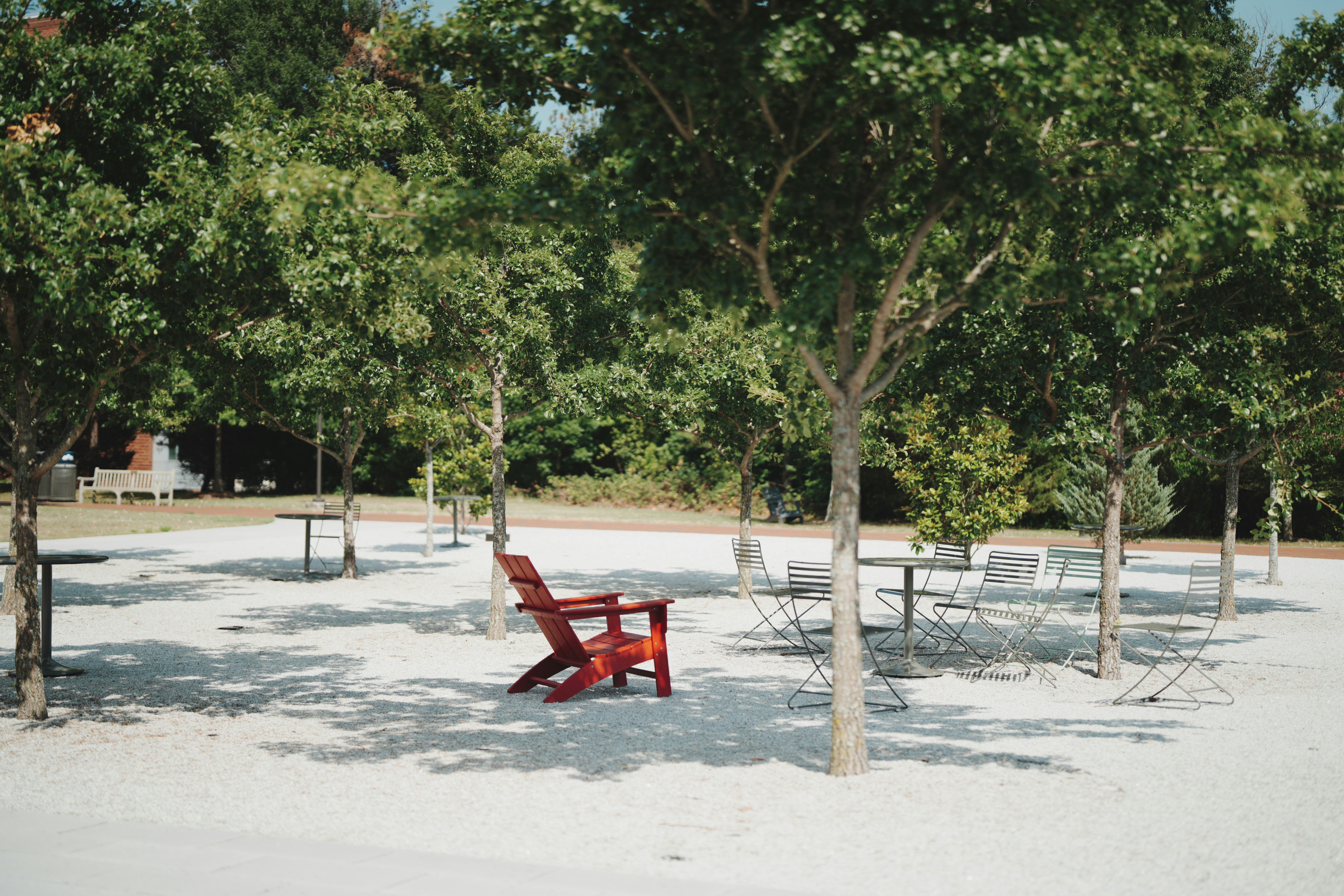 Red chair on white gravel under trees