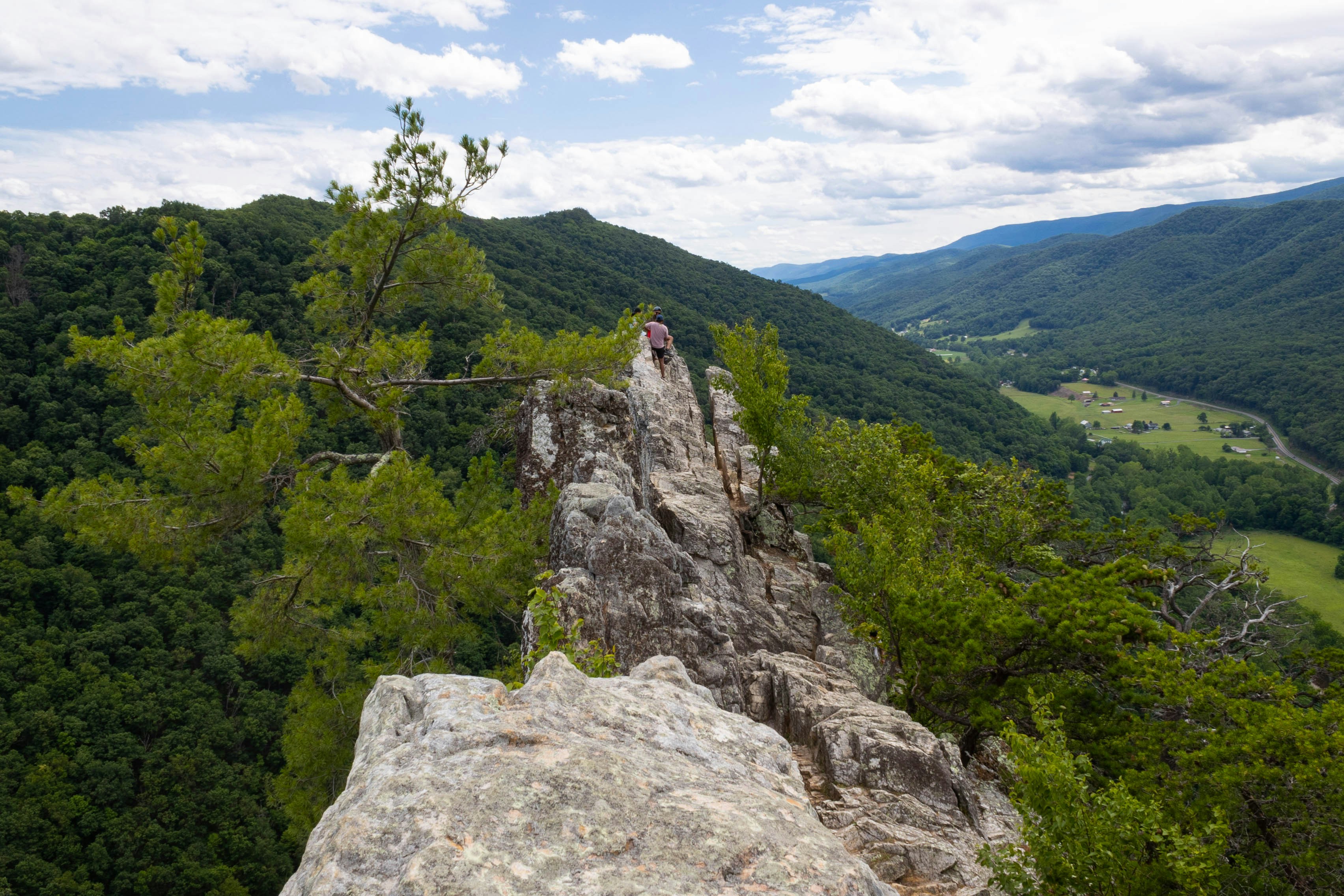 Crista rochosa com vista para um vale verde e montanhas.