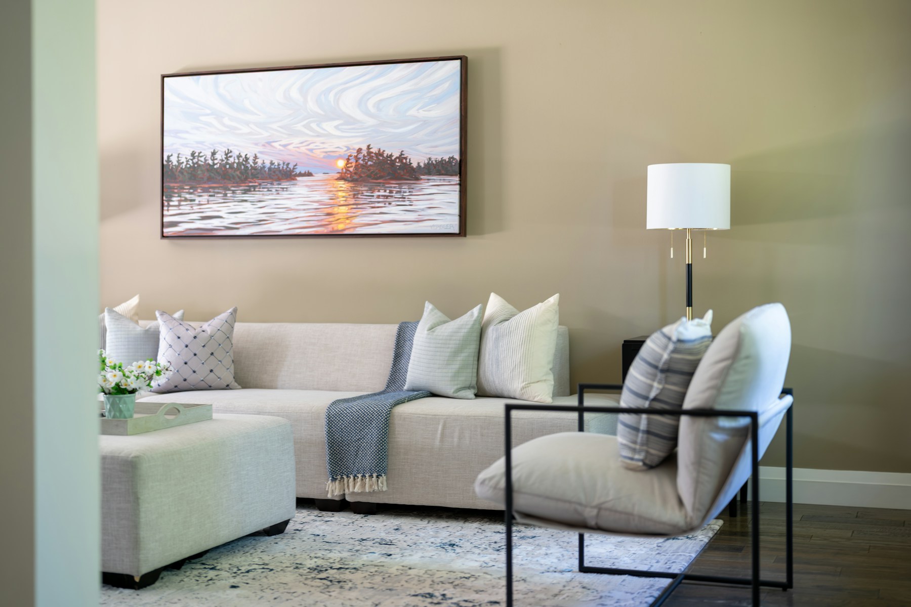 Living room with warm-toned light sofa, armchair and lamp bathed in sunlight