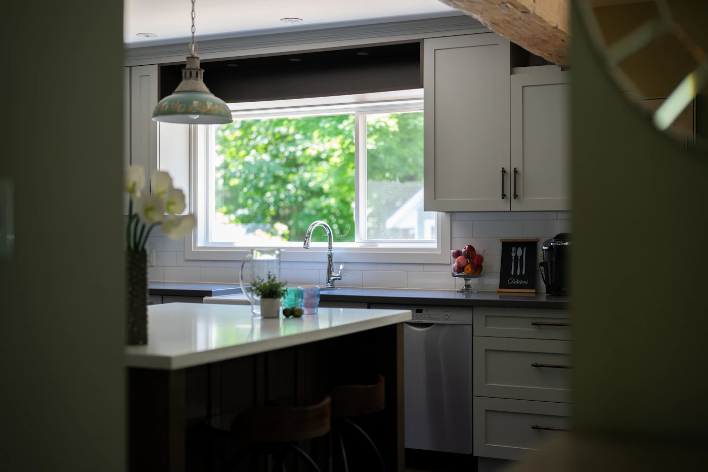 Modern white kitchen cabinetry with a large window and island, shown as design inspiration