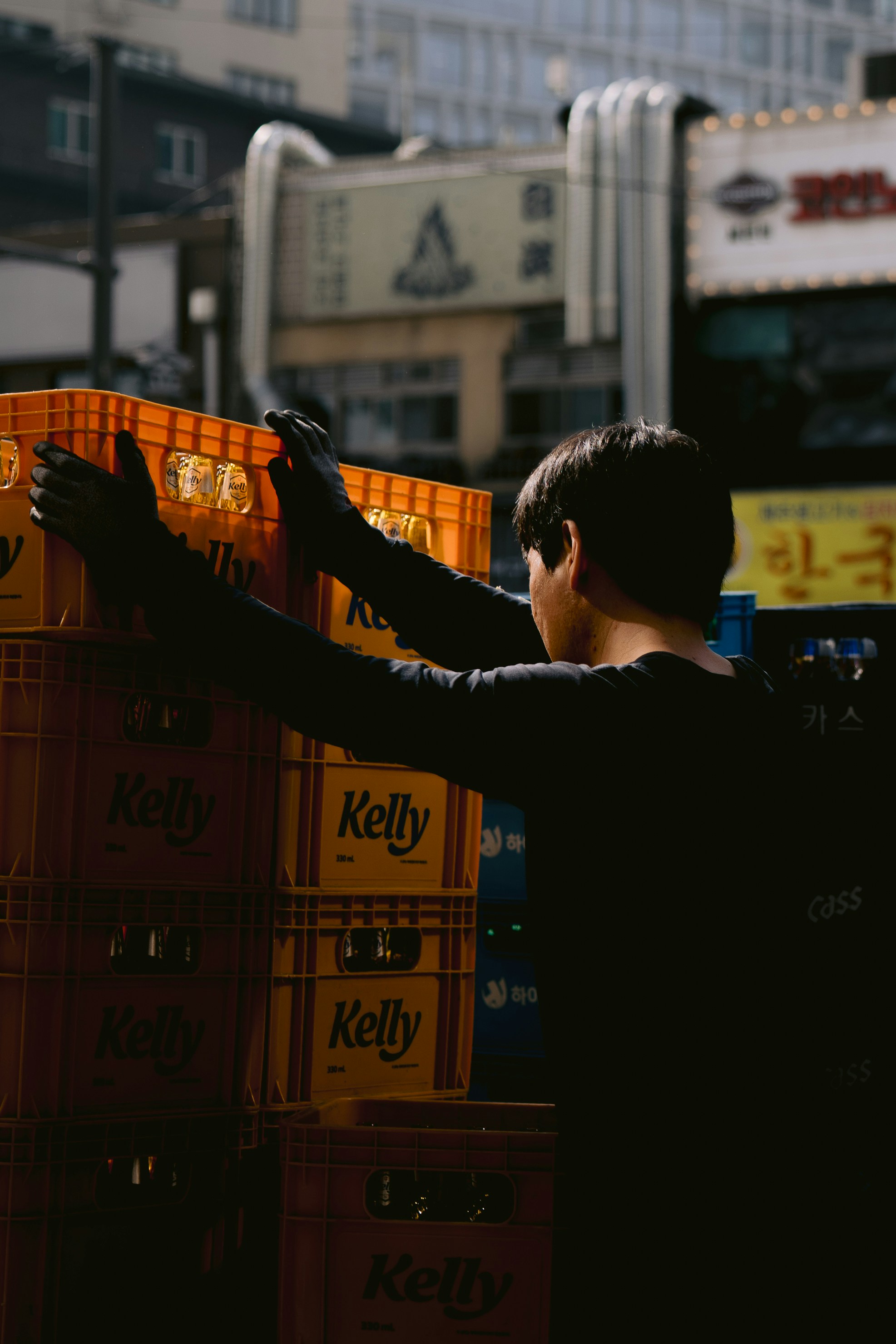 A person stacks orange "kelly" crates in an urban setting.