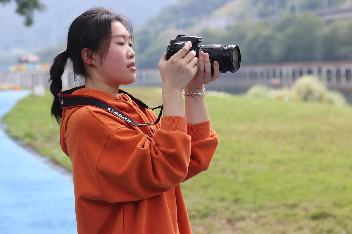 Junge Frau fotografiert draußen mit einer Kamera