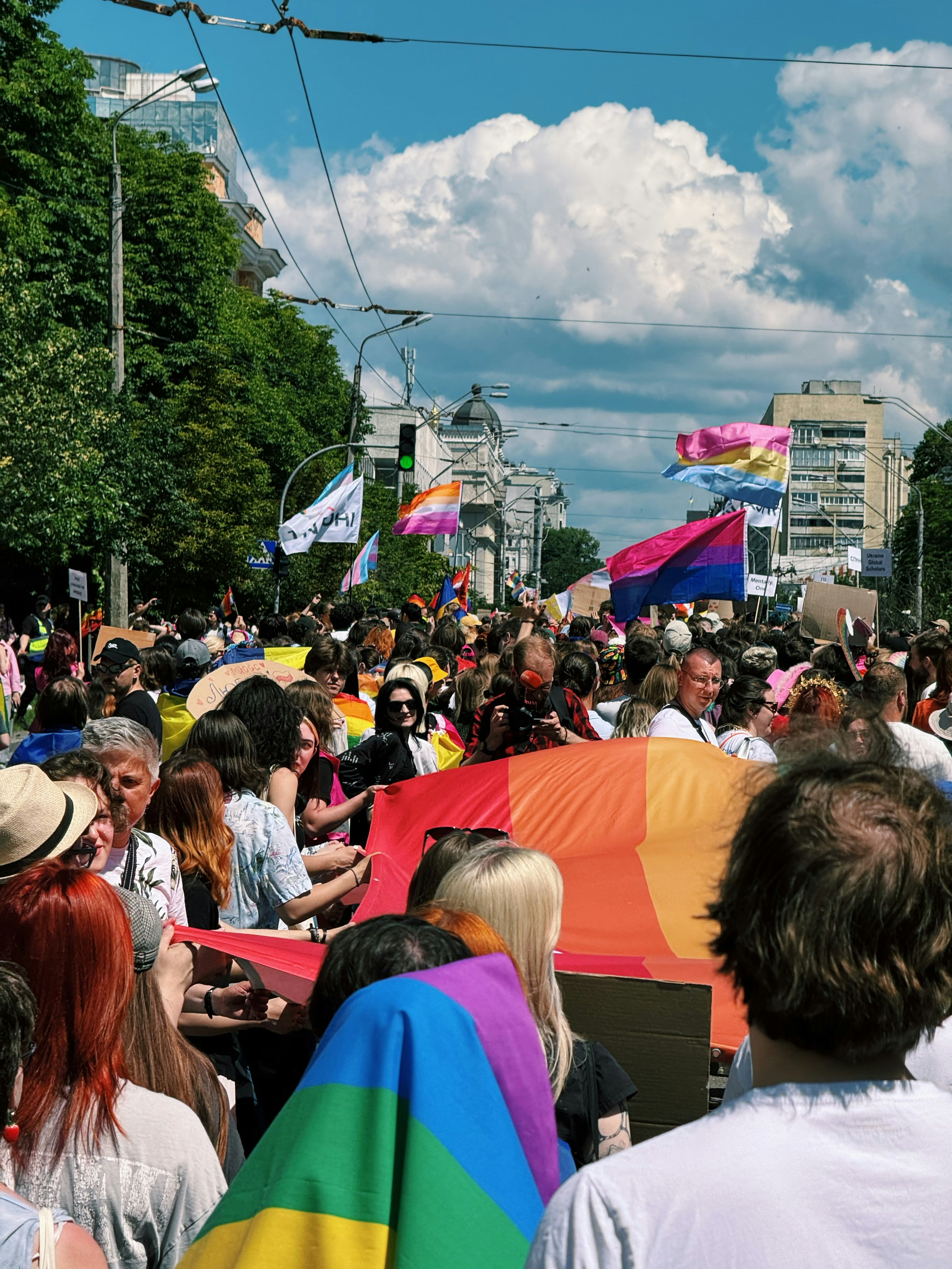 Large crowd of people marching in a vibrant pride parade