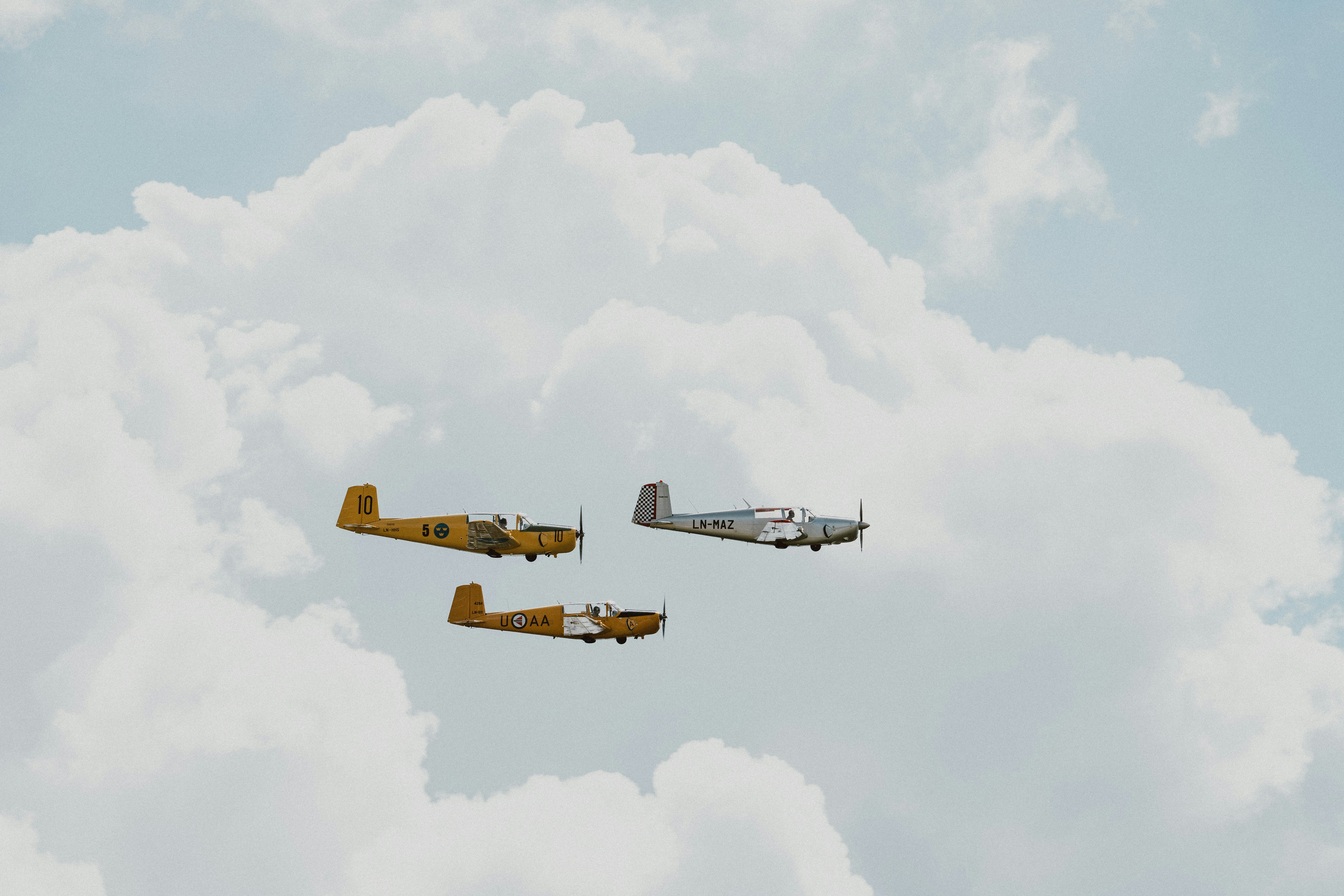 Trois petits avions volant dans un ciel nuageux.