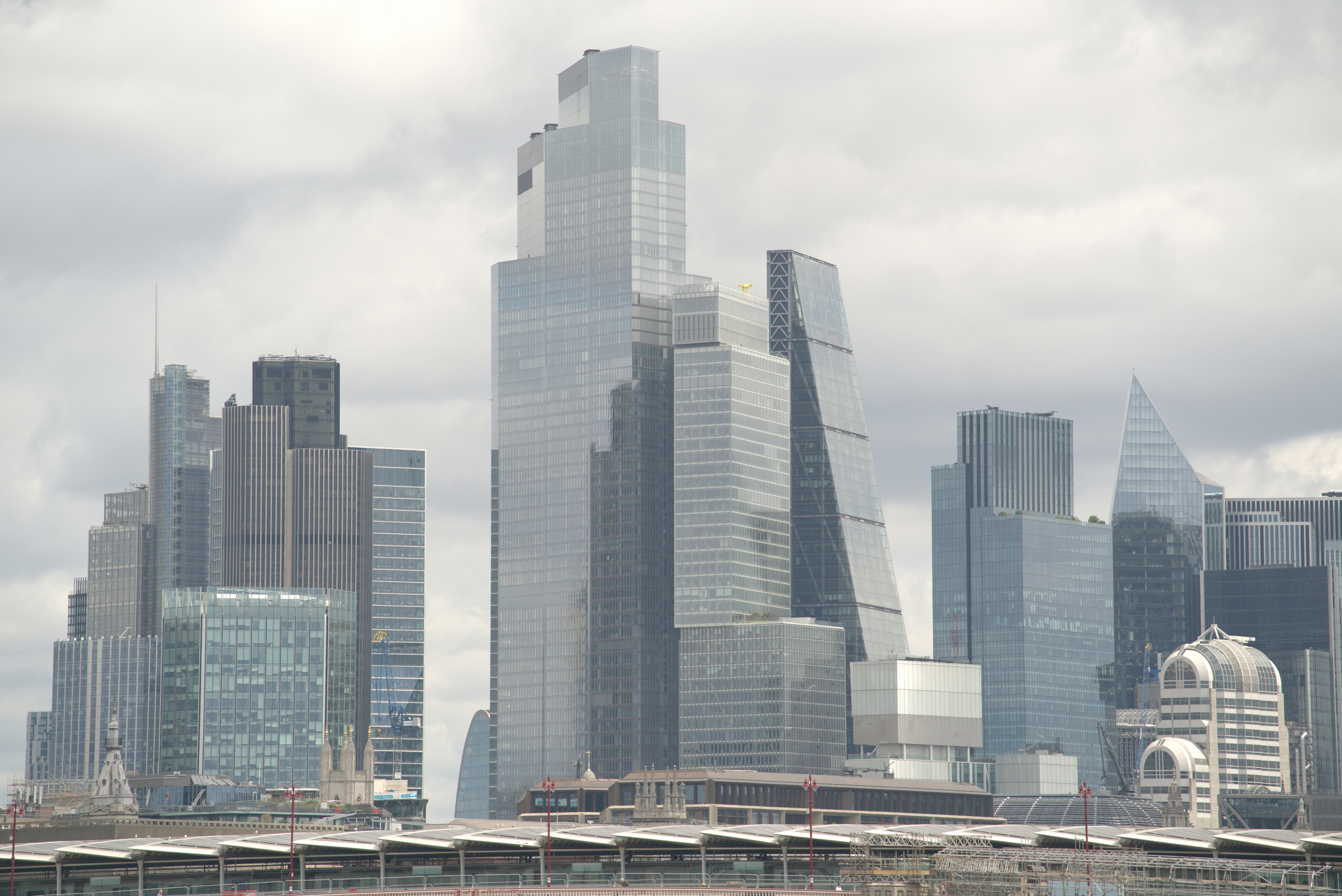 Modern skyscrapers dominate the city skyline under a cloudy sky.