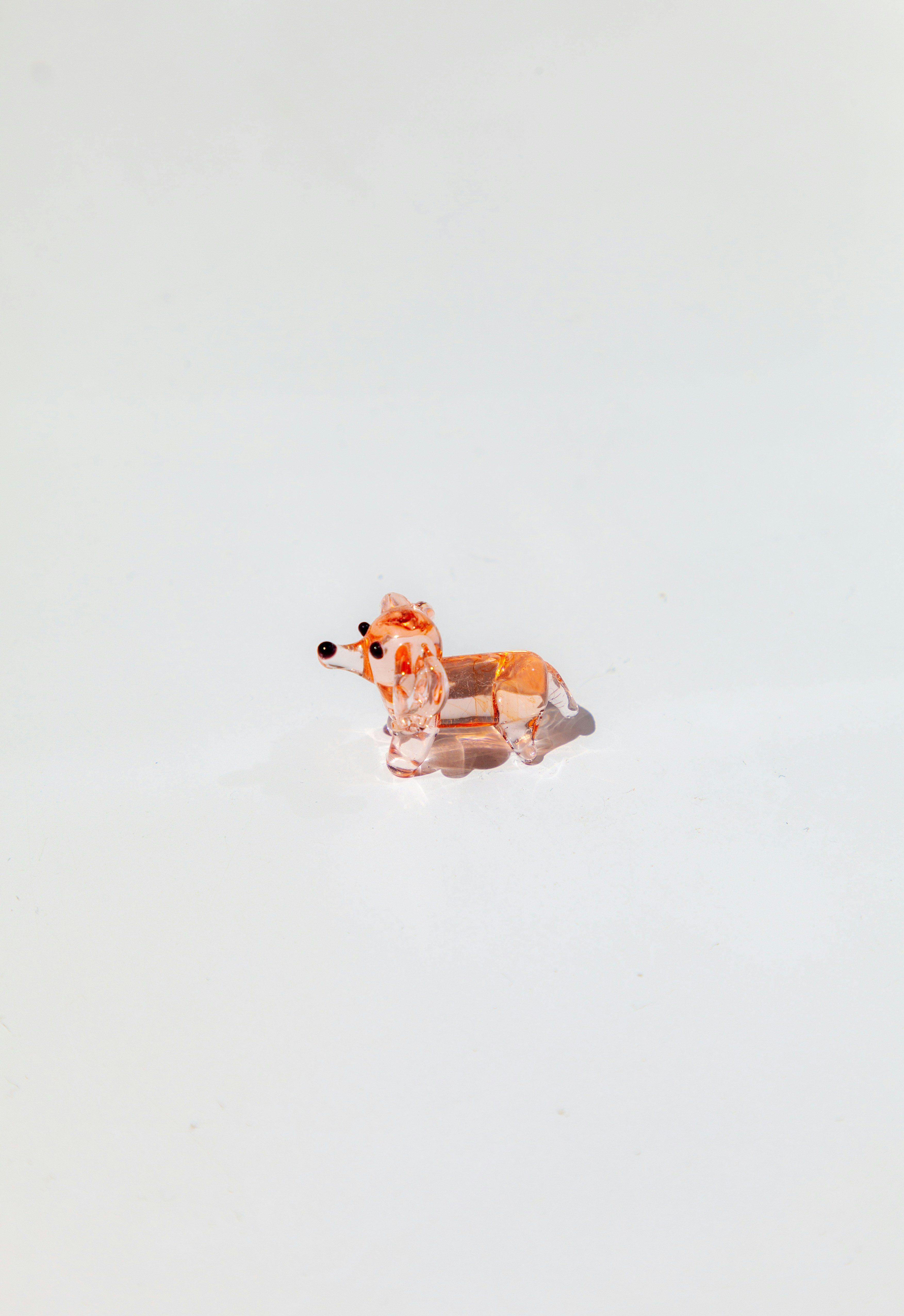 Patung anjing kaca kecil dengan latar belakang putih.