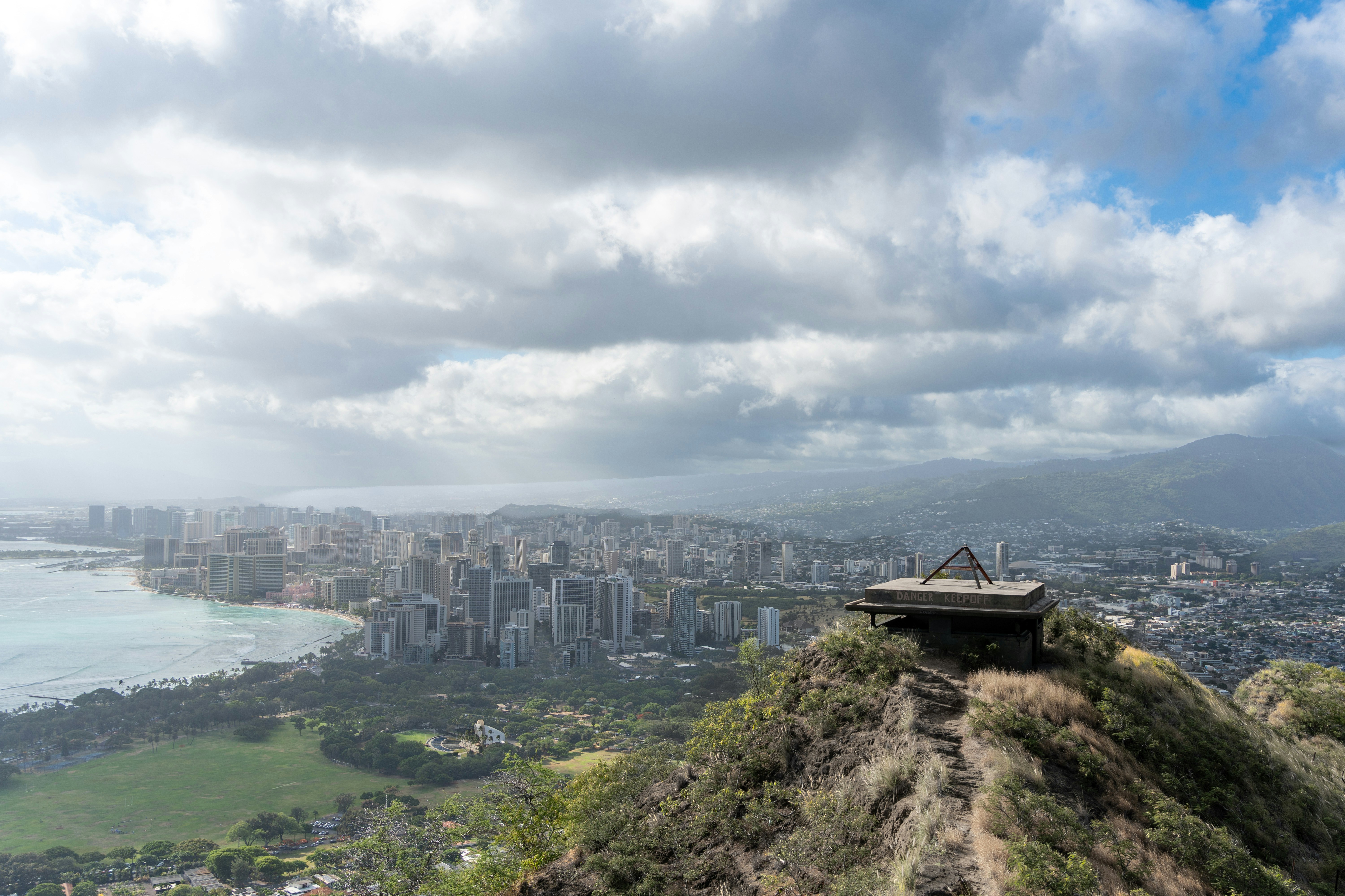 City skyline, bay, and ridge structure under cloudy sky.