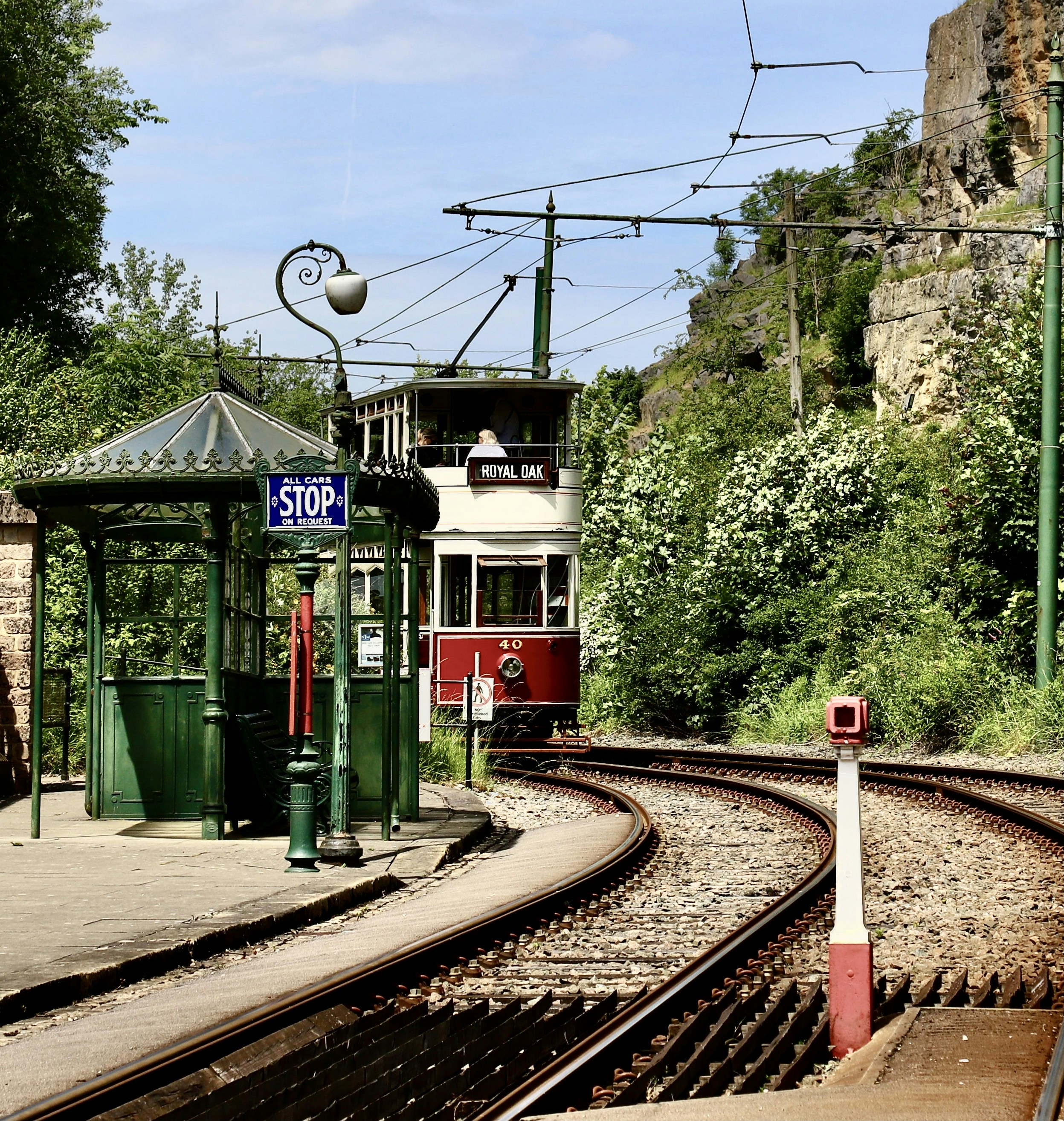 Vintage tram at a green stop with curved tracks.