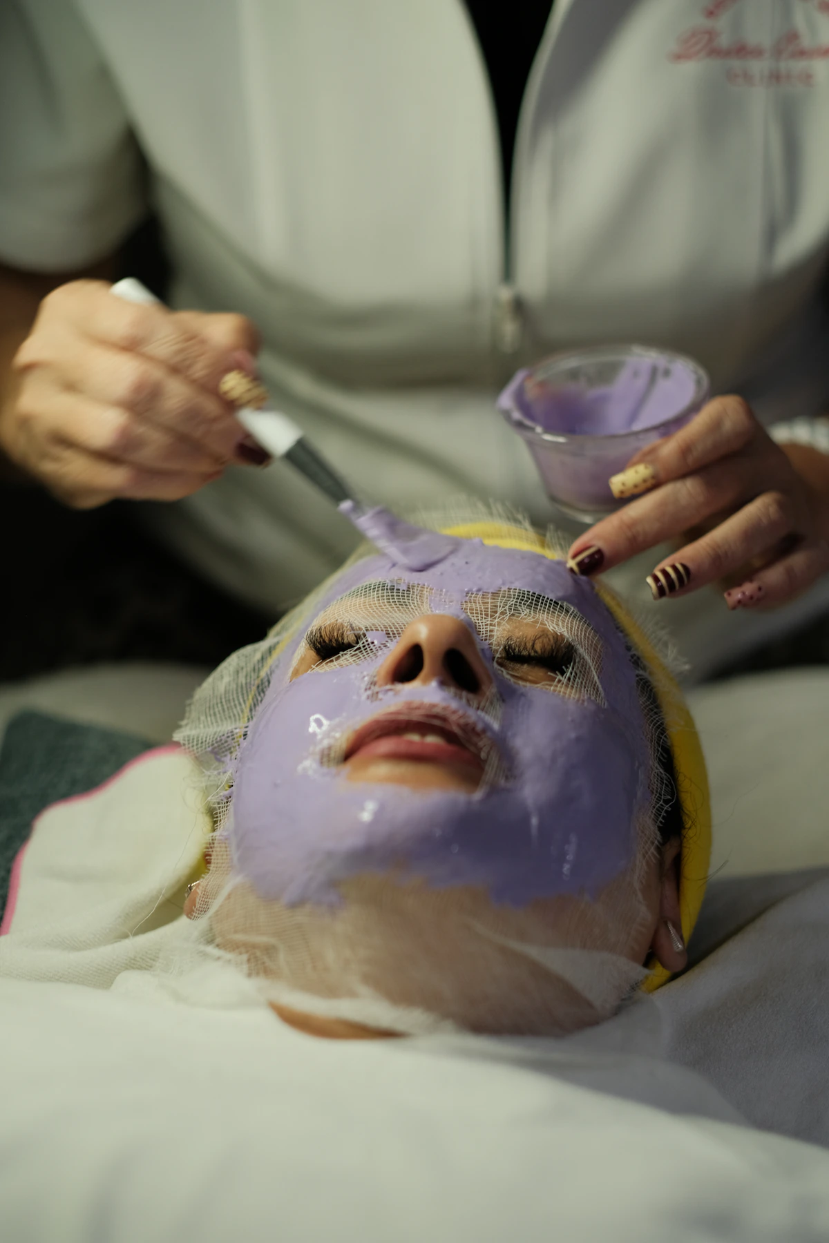Esthetician applying a resurfacing facial mask to a client