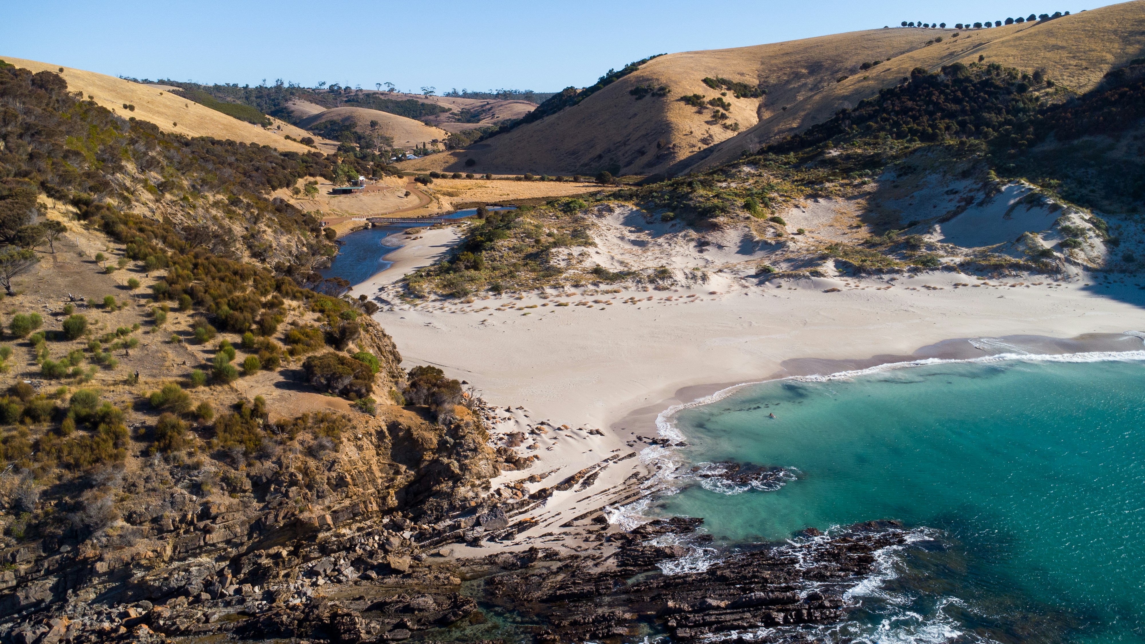 A secluded white sand beach with turquoise water and hills.
