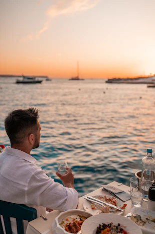 Man enjoying sunset dinner by the sea in fira
