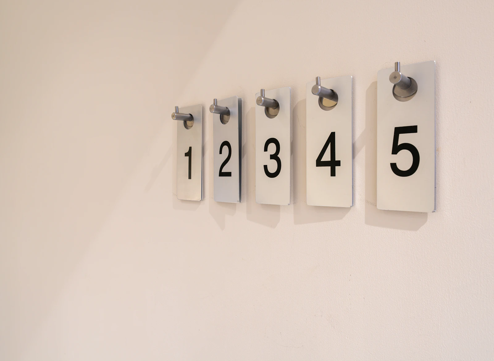 Five cards numbered one to five, in a row on a pale wall