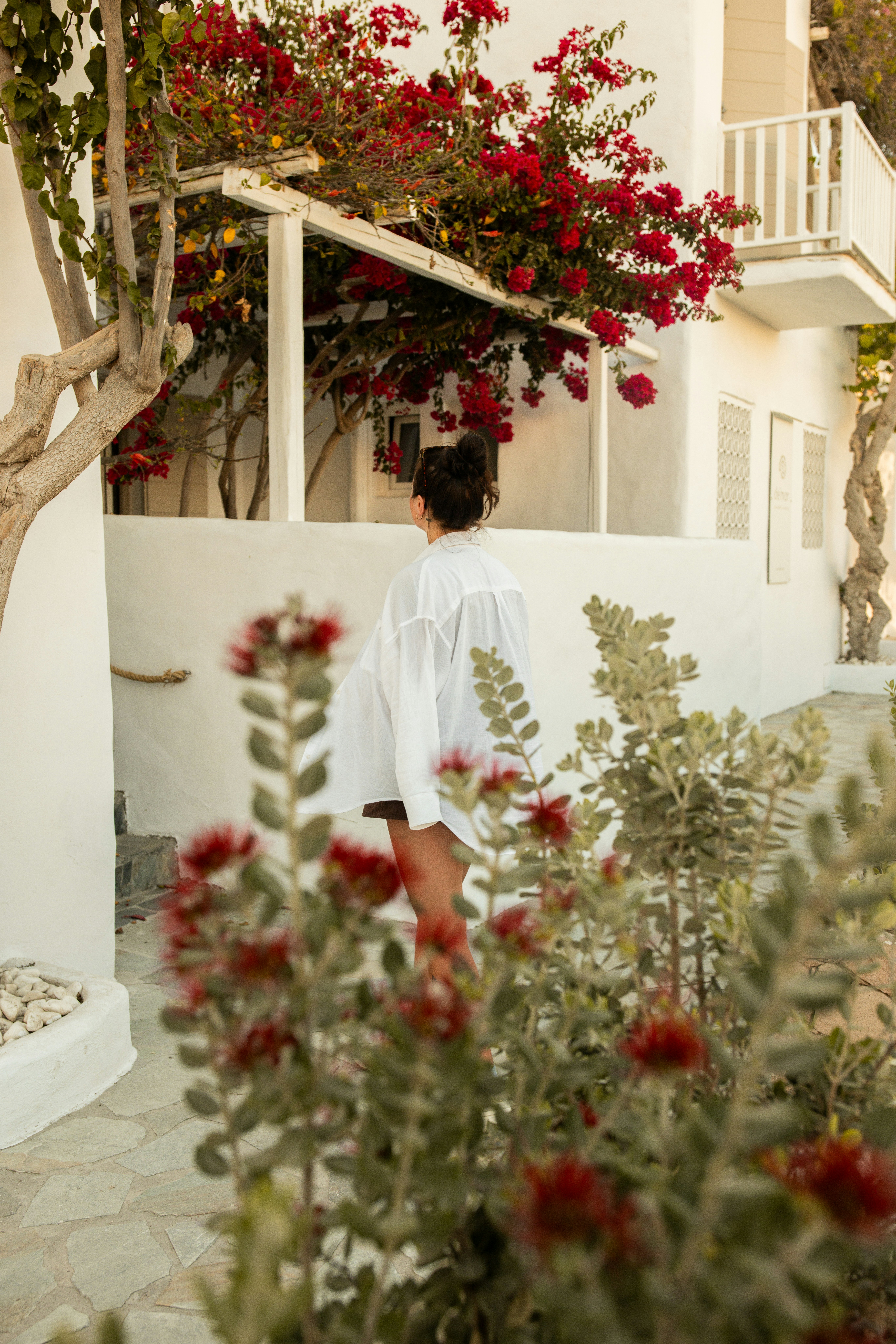 A woman walks through a sun-drenched Mediterranean alley, vibrant and at ease
