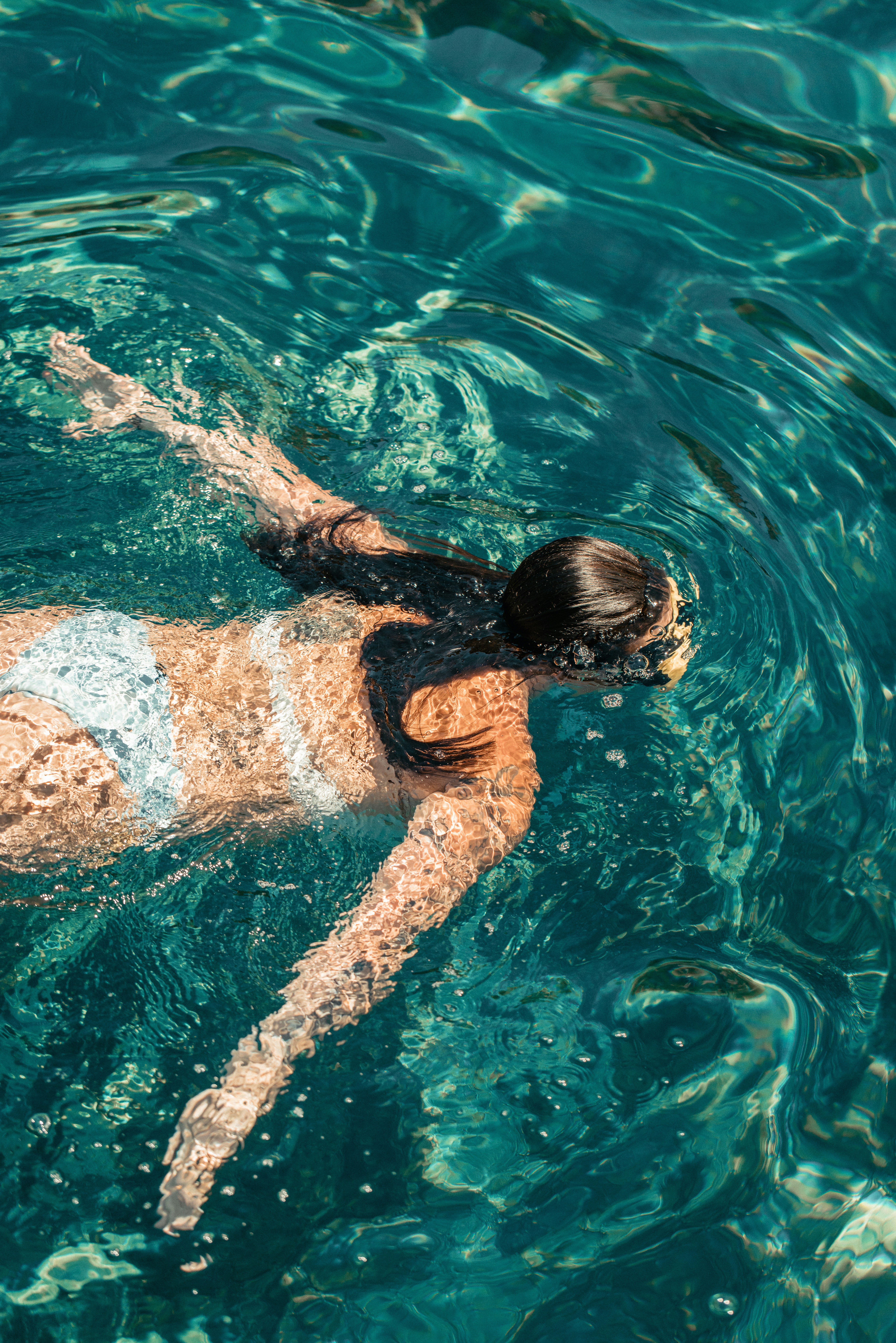 Woman swimming in clear blue waters, milos, greece