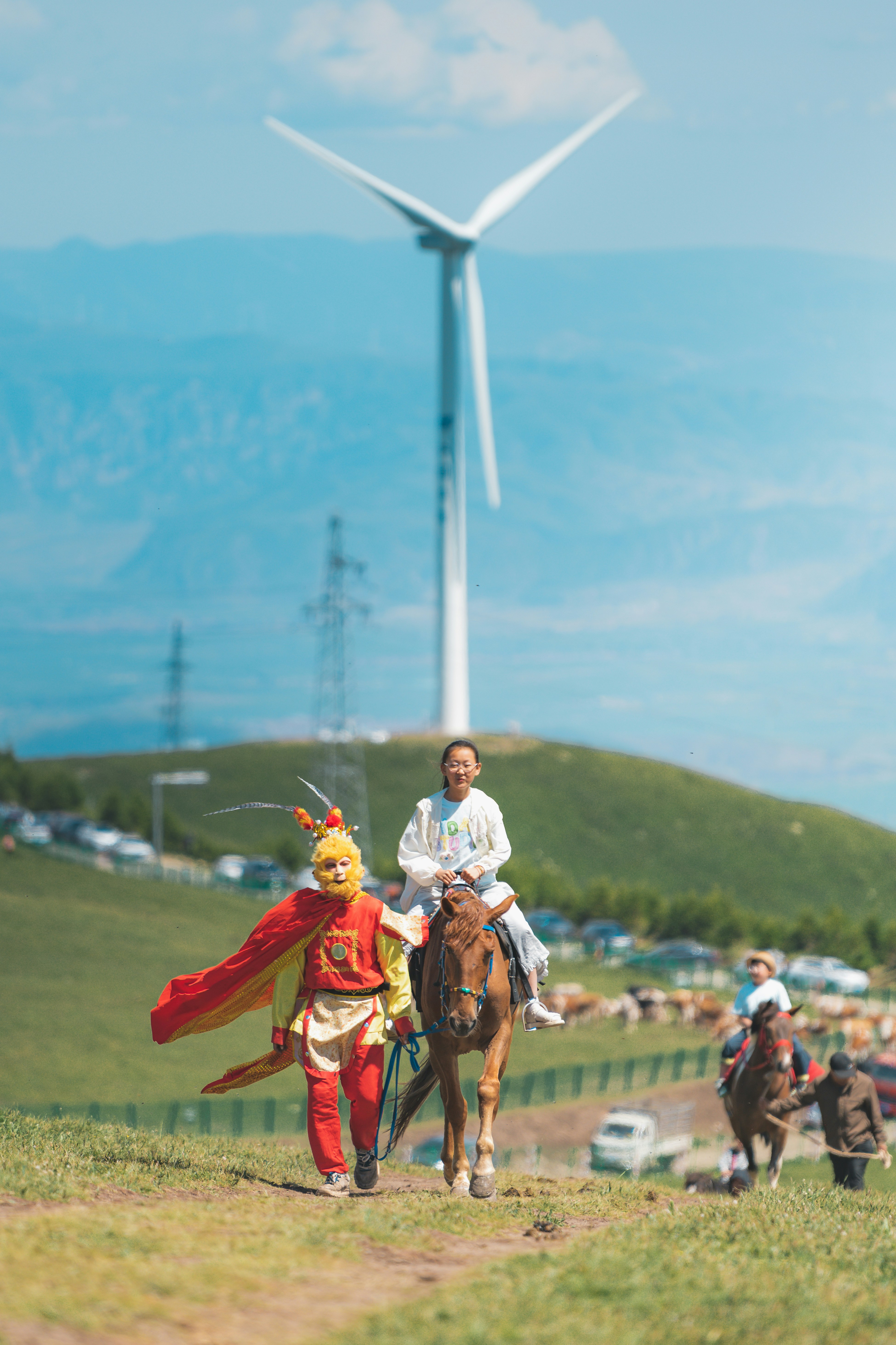 Personnage costumé et cavalier à cheval près d’une éolienne.