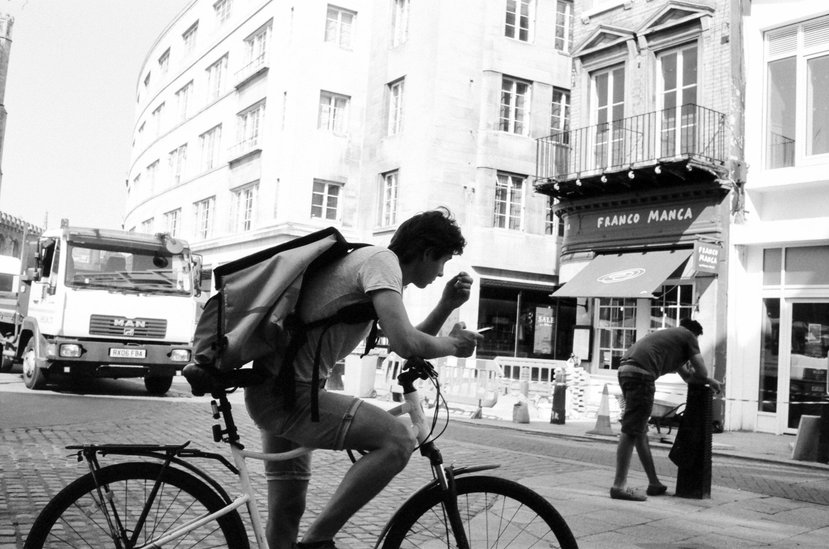 Cyclist checking phone on a busy city street.