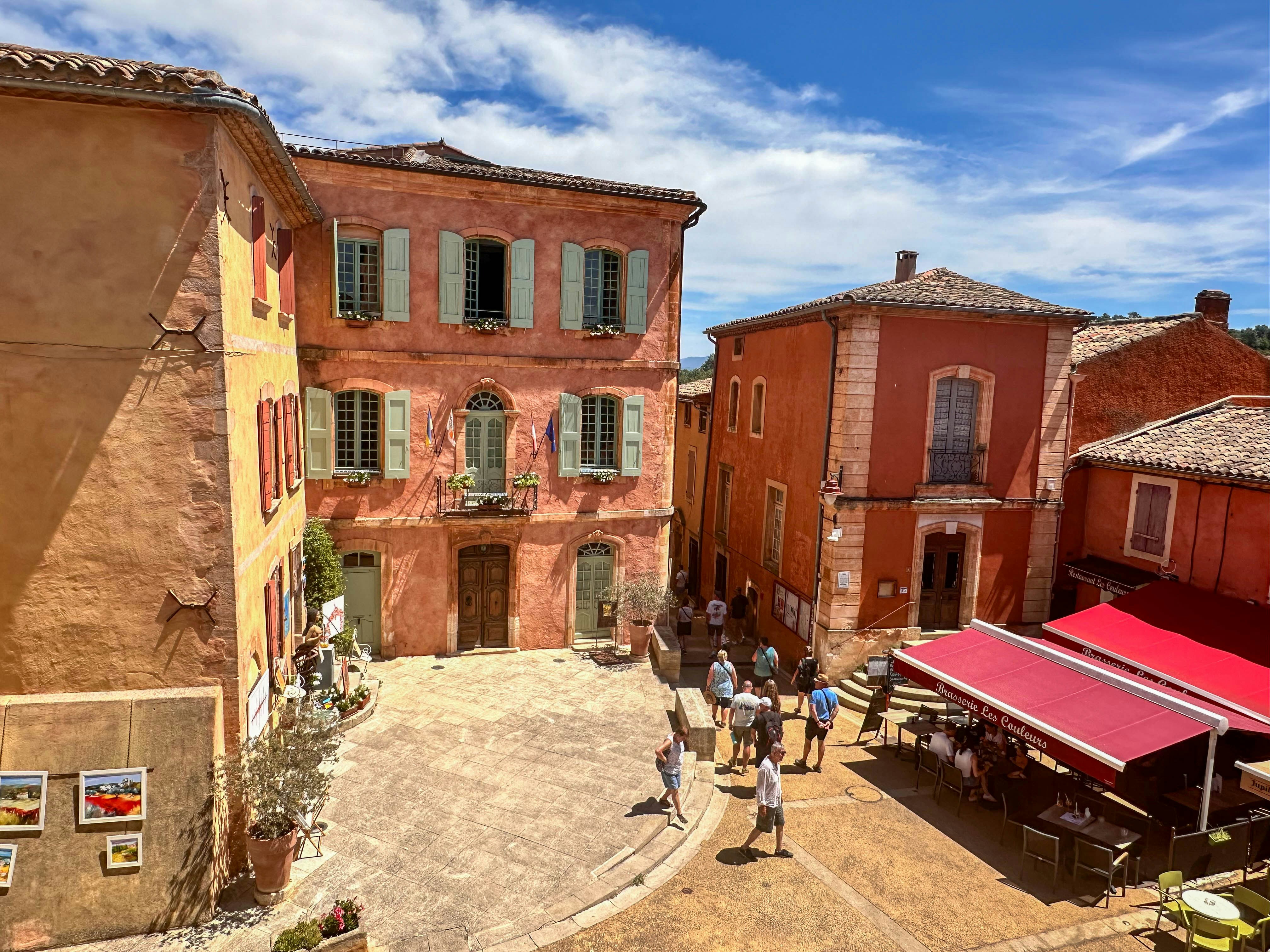 Colorful buildings surround a bustling town square under blue sky.