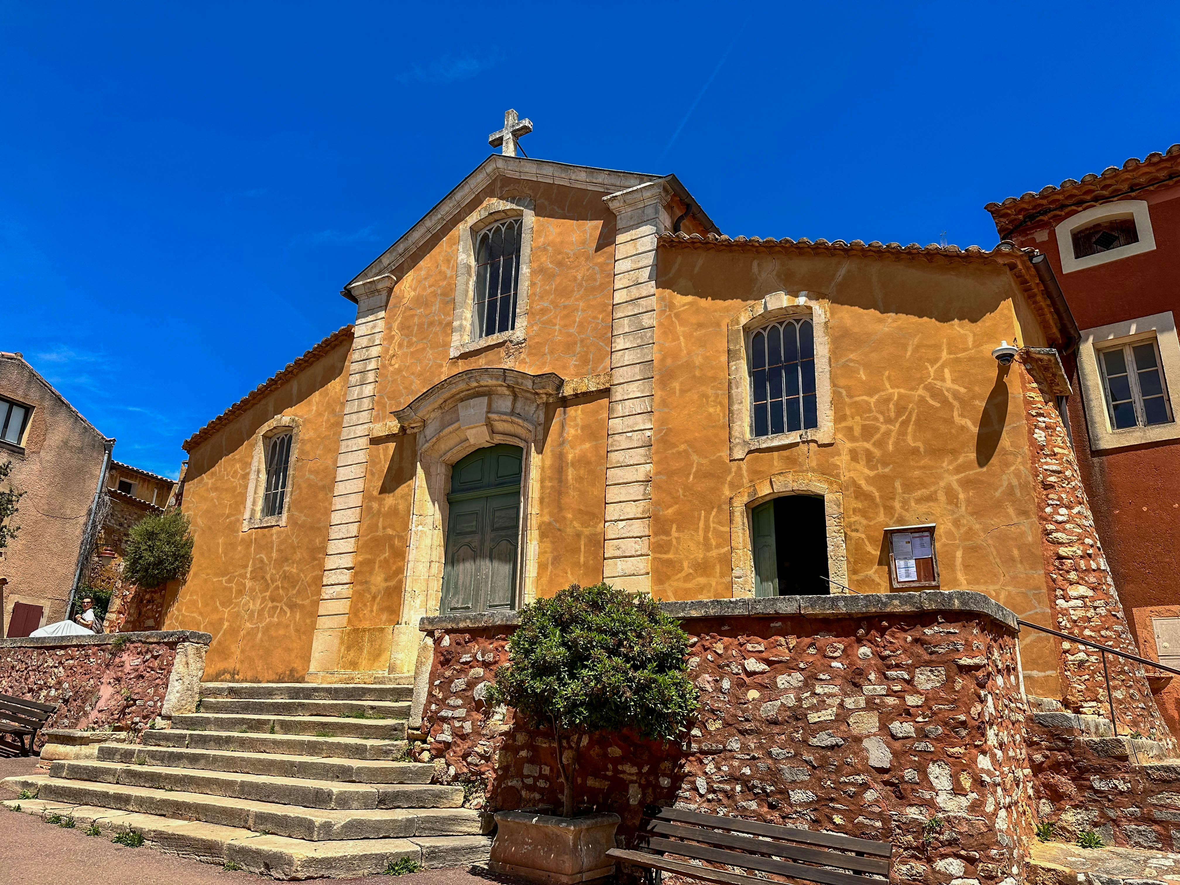 Old orange church with stone steps under blue sky.