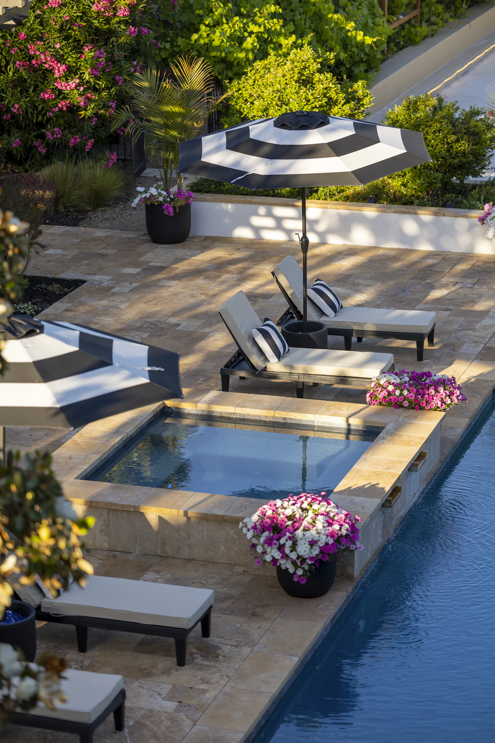 A raised stone spa beside a dark lap pool
