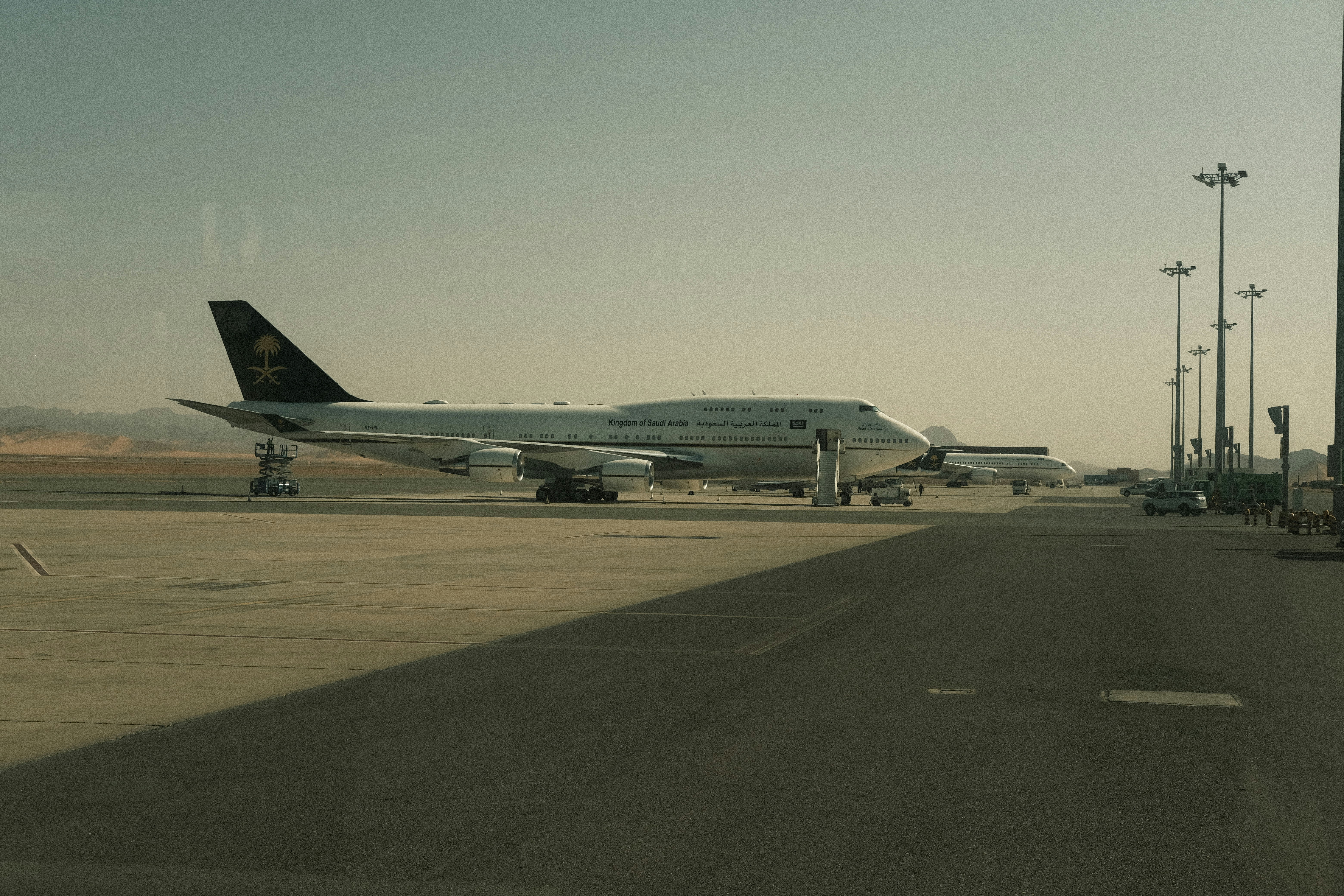 A large airplane parked on an airport tarmac under sunlight.
