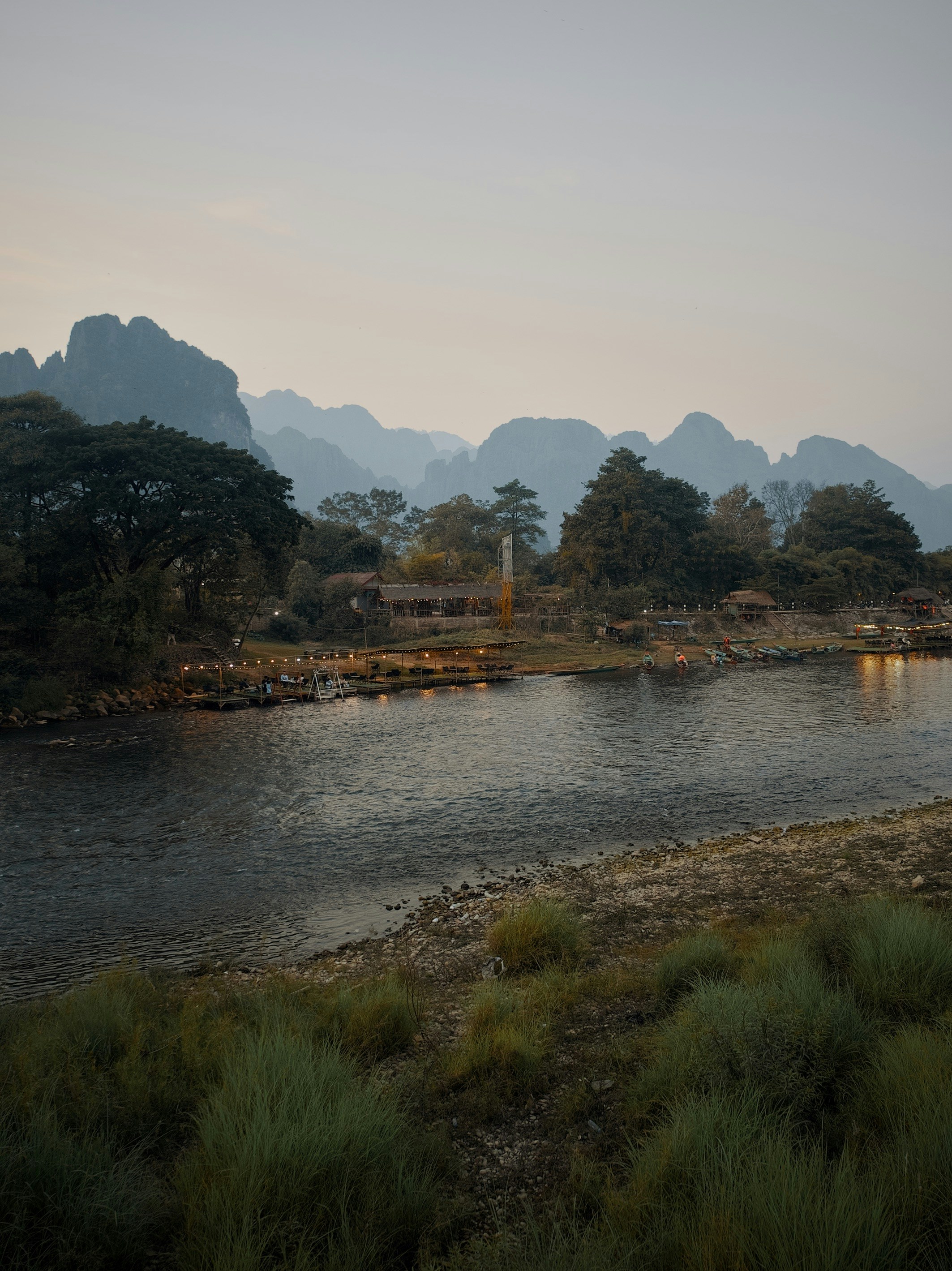 River flowing past a village with mountains in the distance.