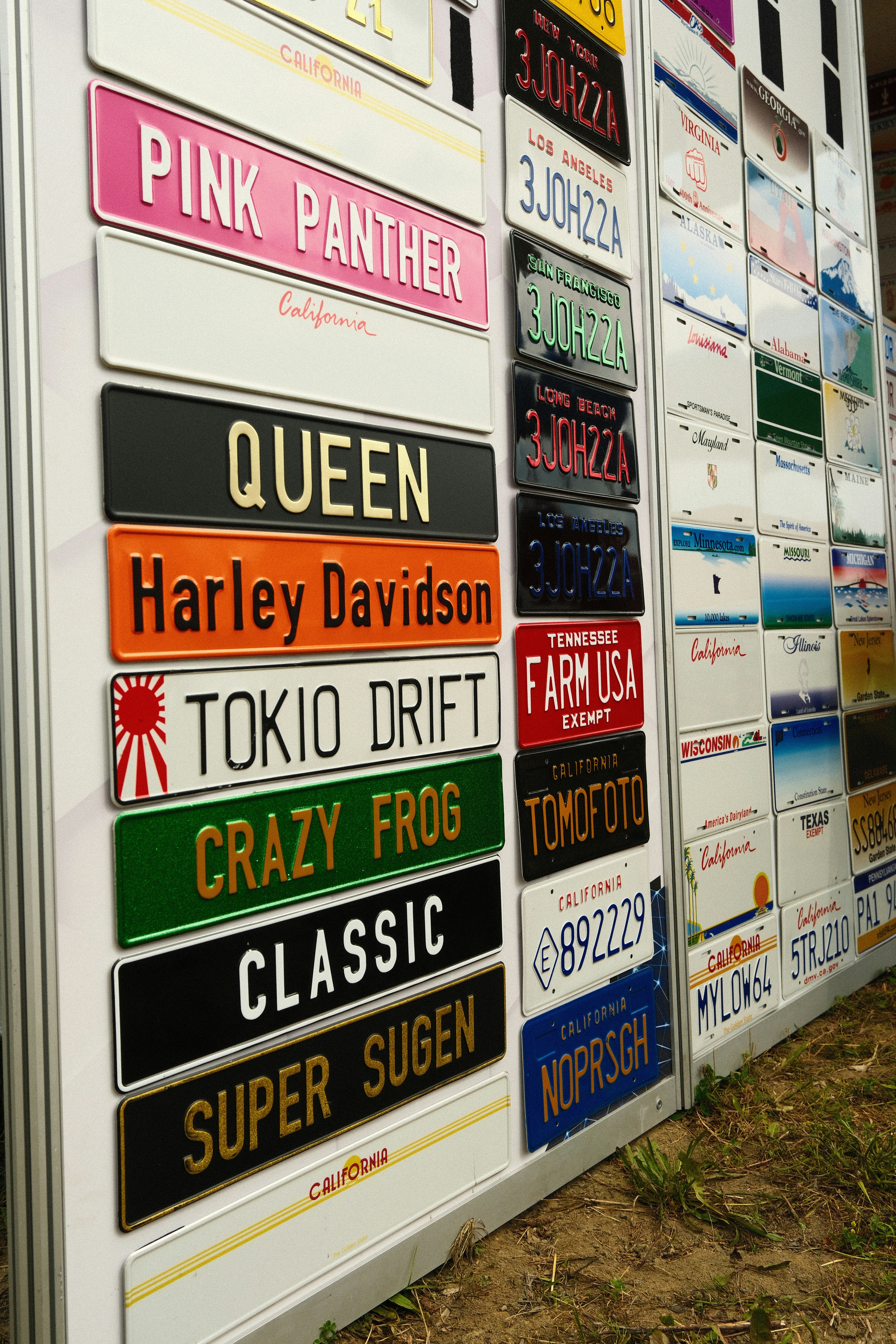 Collection of various novelty license plates displayed on an outdoor wall.