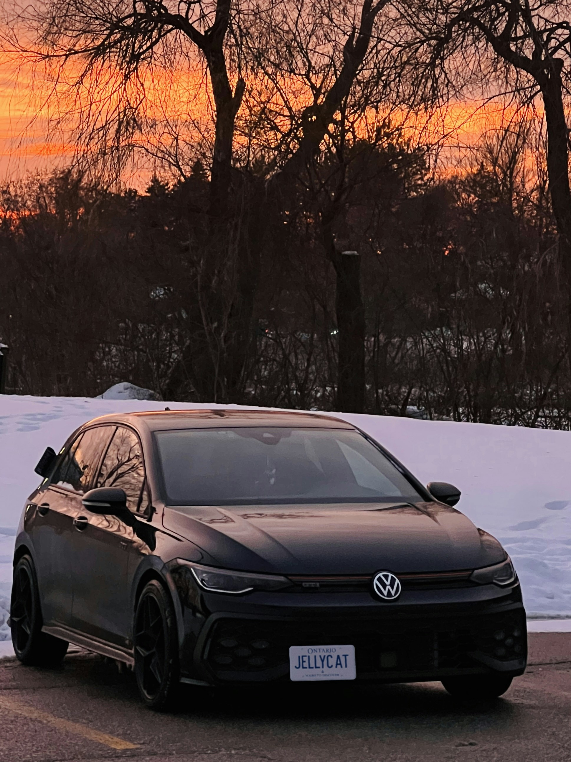 Black volkswagen golf r parked during a vibrant winter sunset.