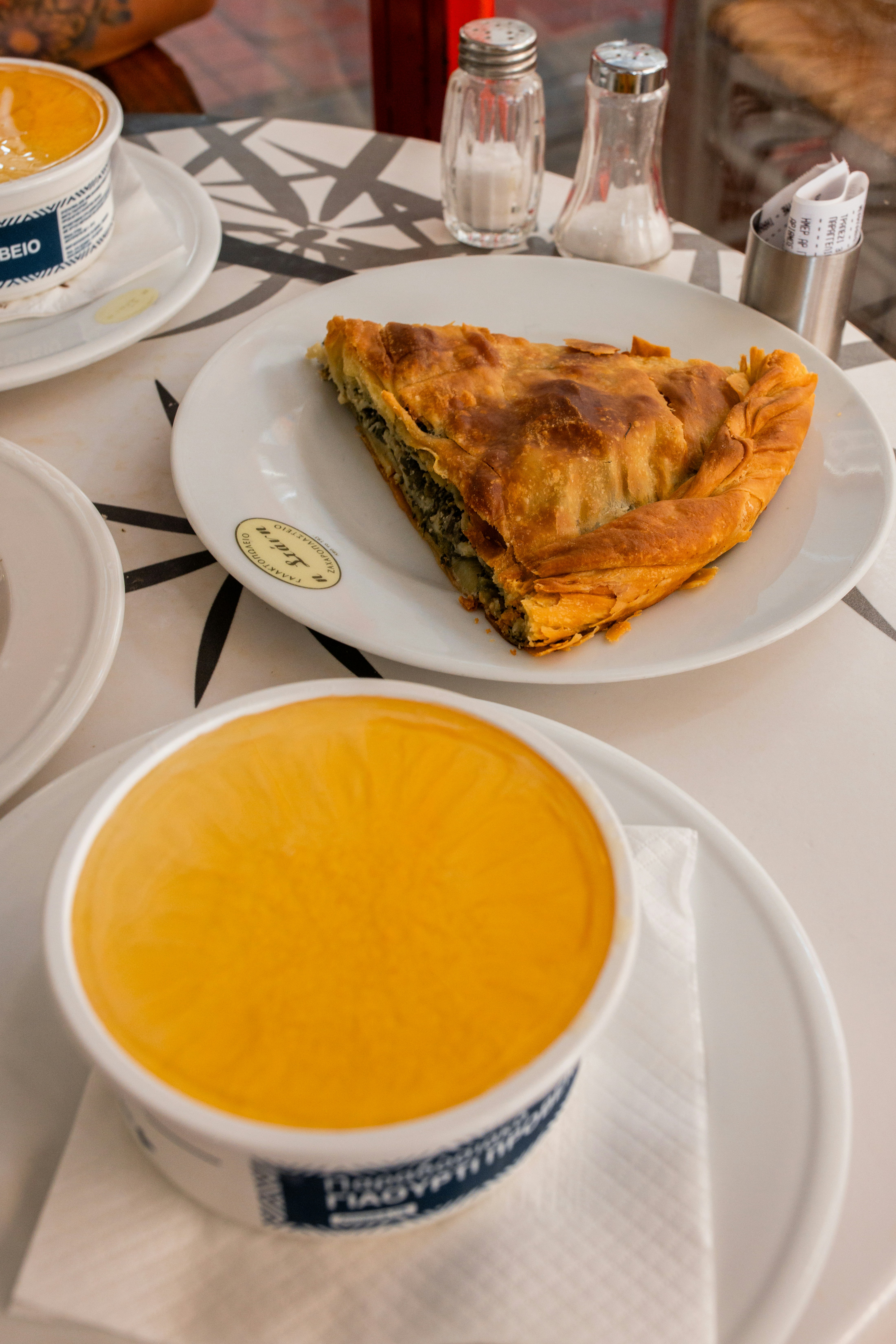 Baked spanakopita triangle with golden phyllo crust on white plate`