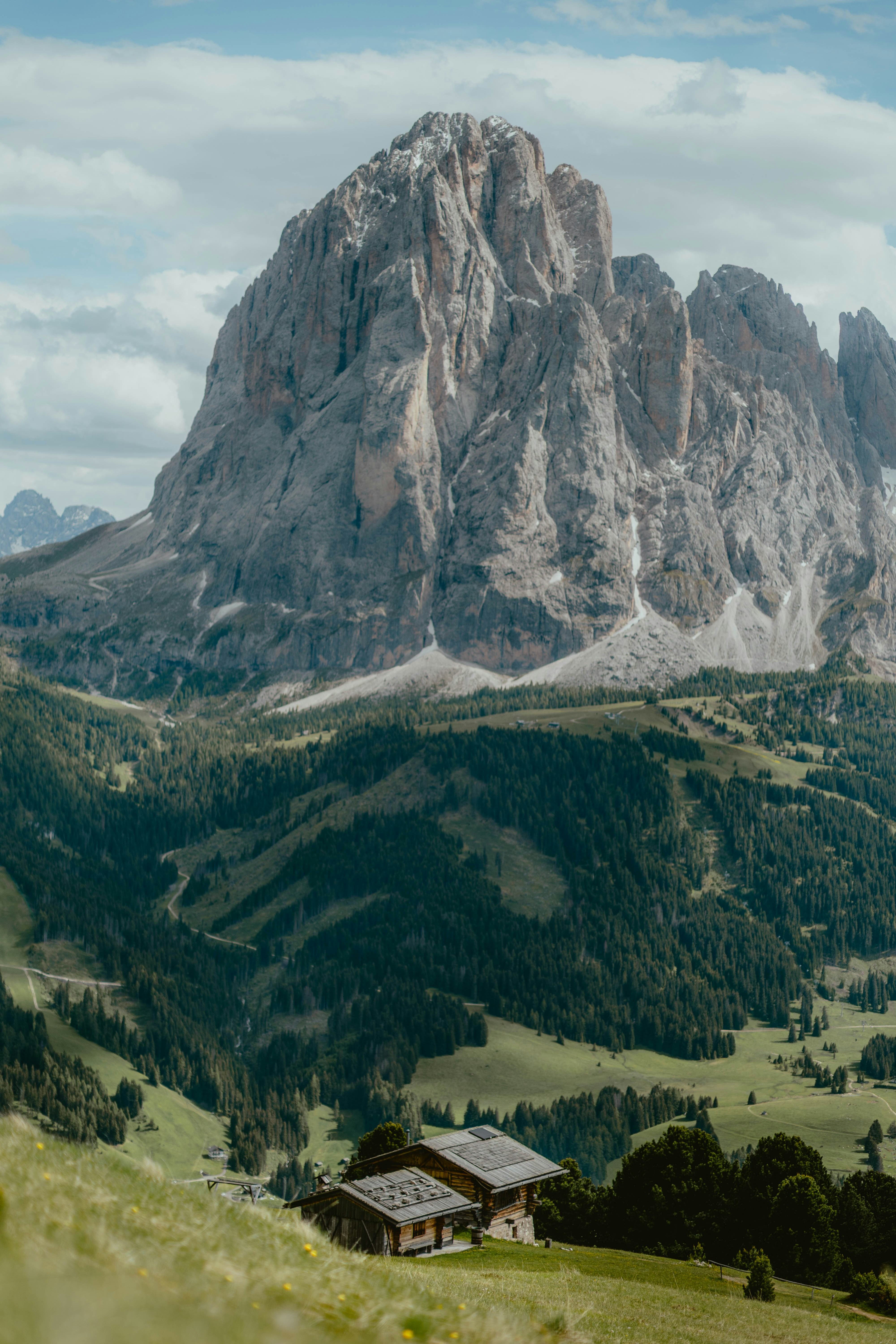Alpine house nestled in a valley beneath a towering mountain.