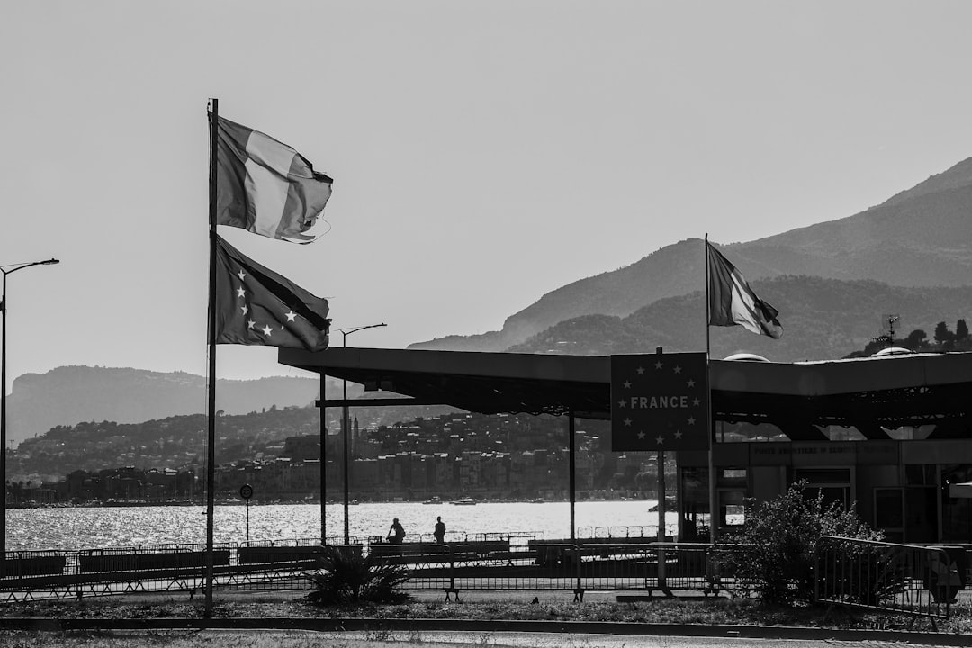 Border crossing with french and eu flags near mountains.