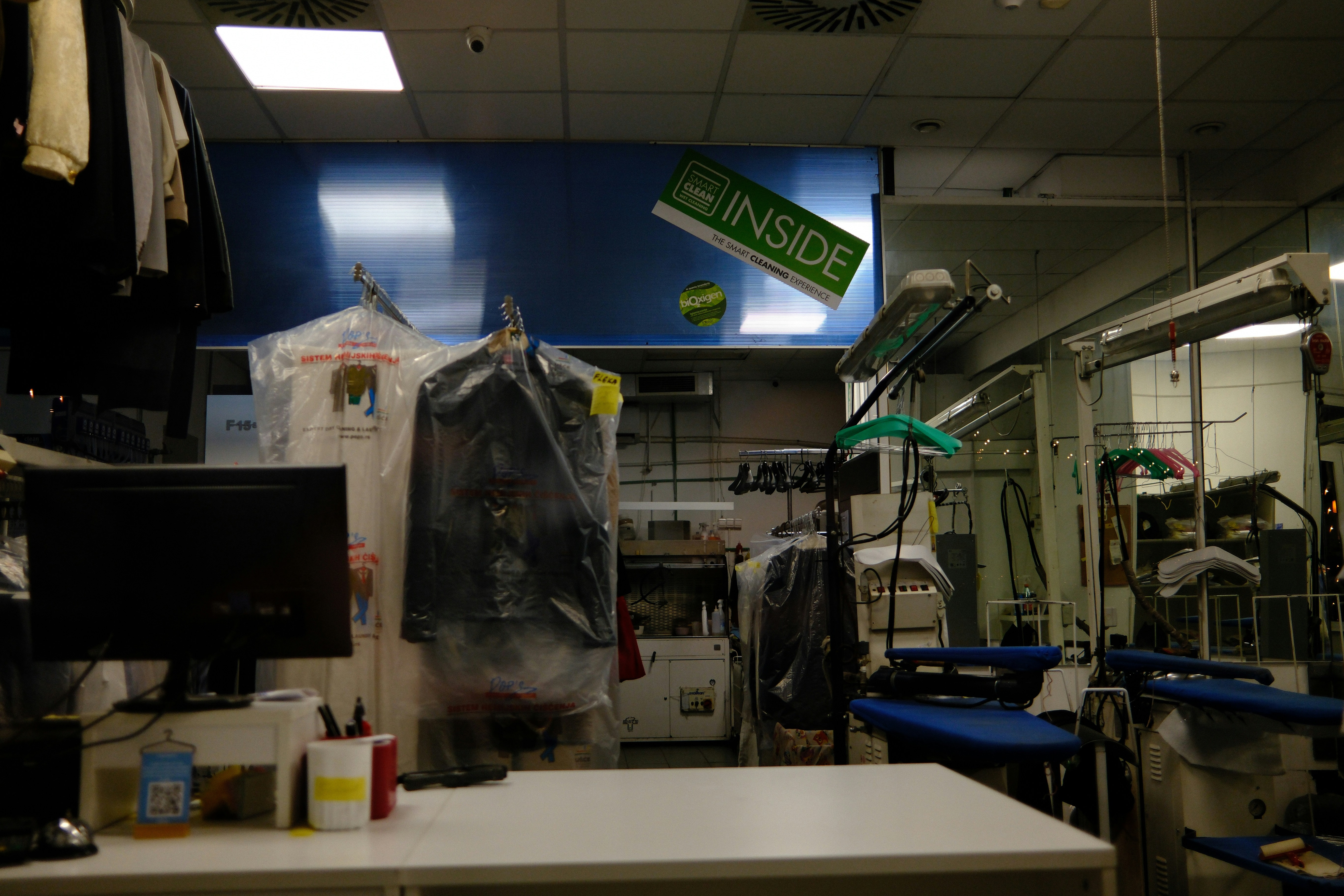 Interior of a dry cleaning shop with clothes and equipment.