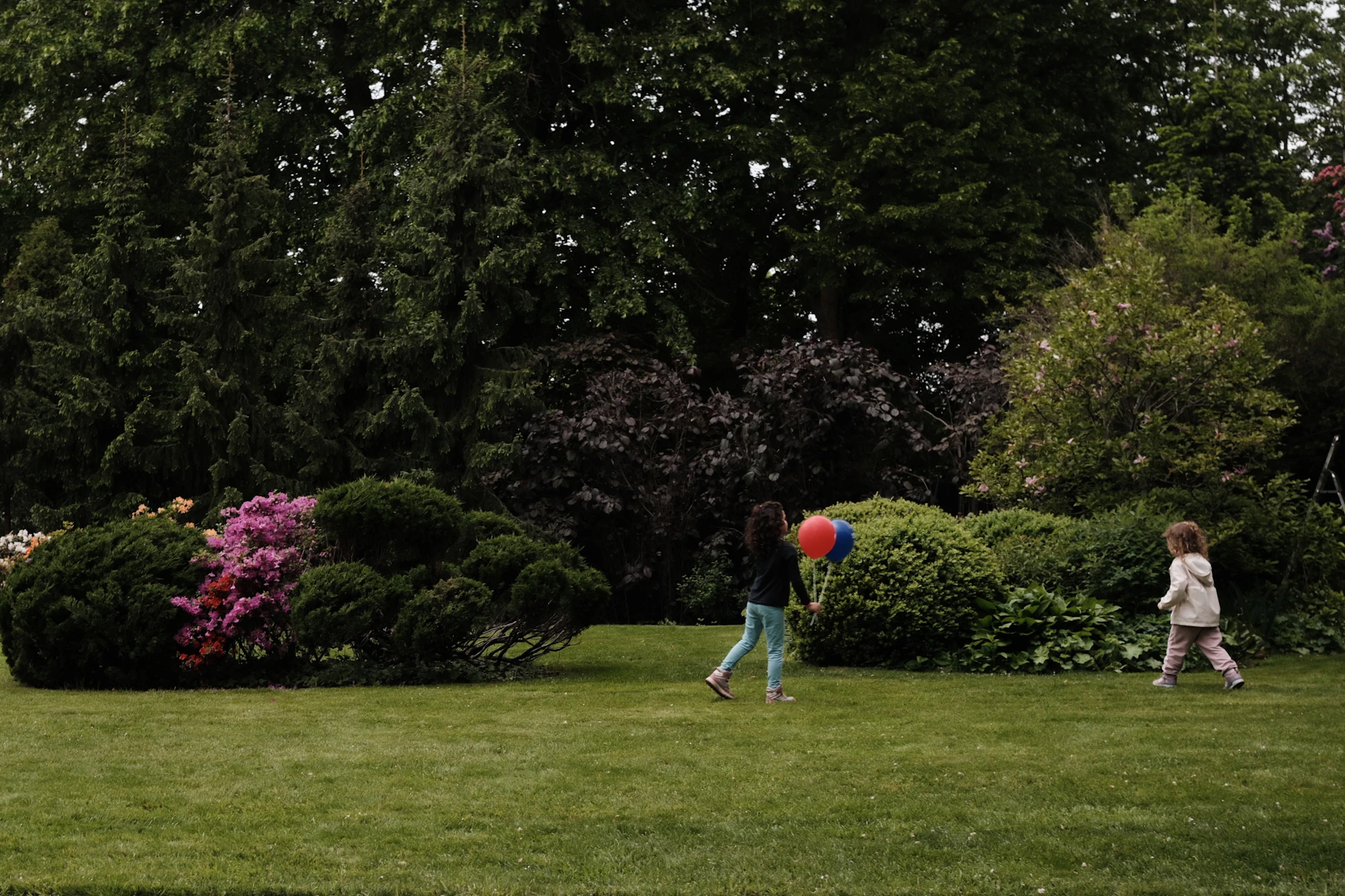 Two children playing with a balloon on a green lawn