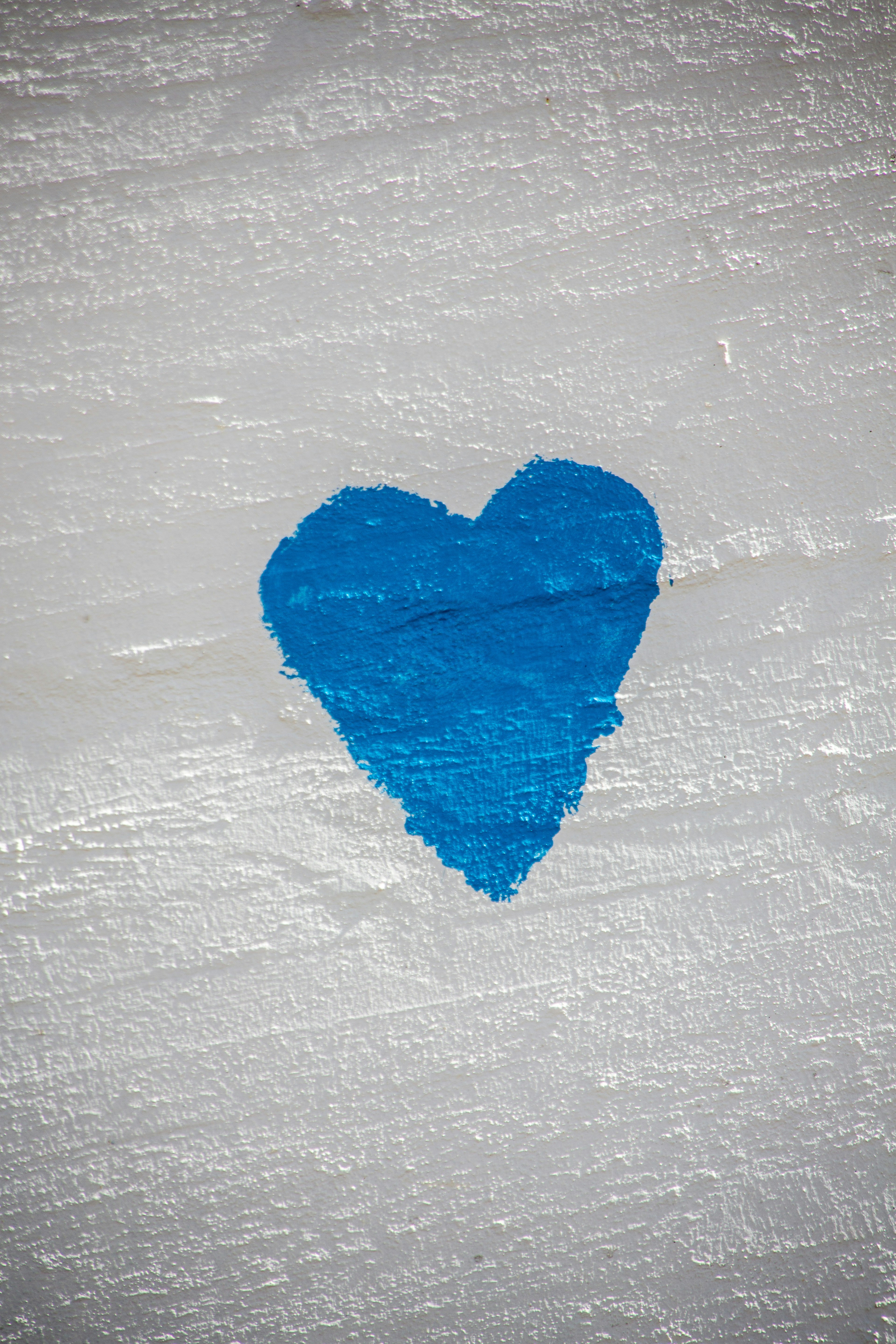 Ein blaues Herz, das auf einem strukturierten weißen Hintergrund gemalt ist.