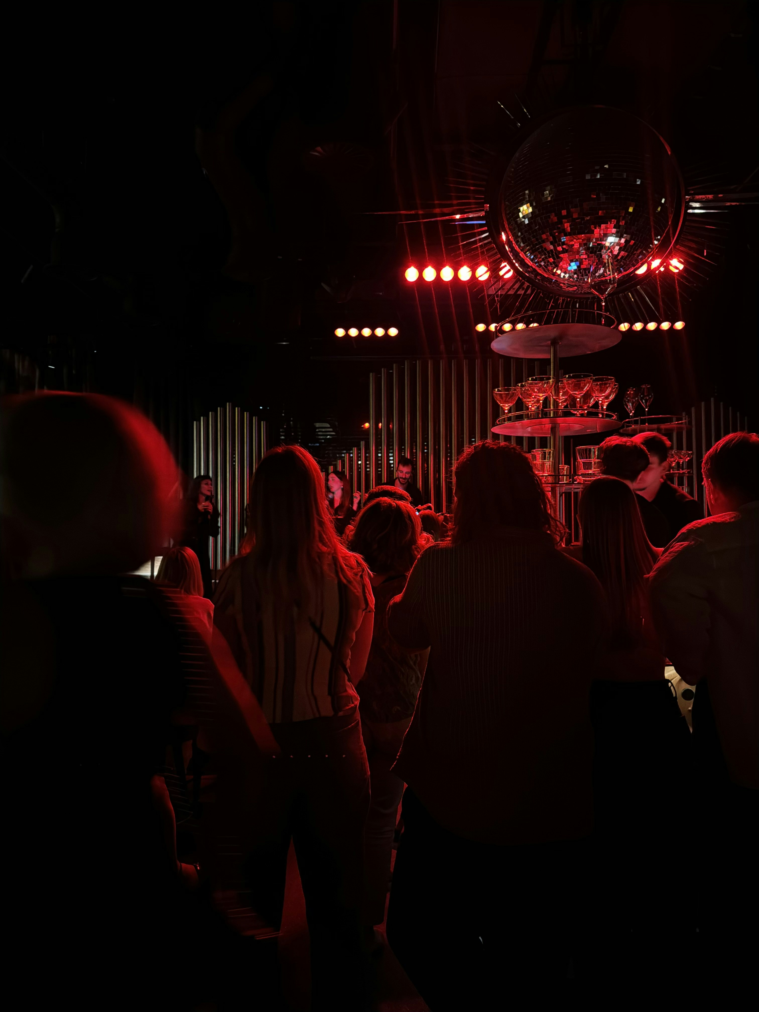 Silhouetted audience at a concert with a disco ball.