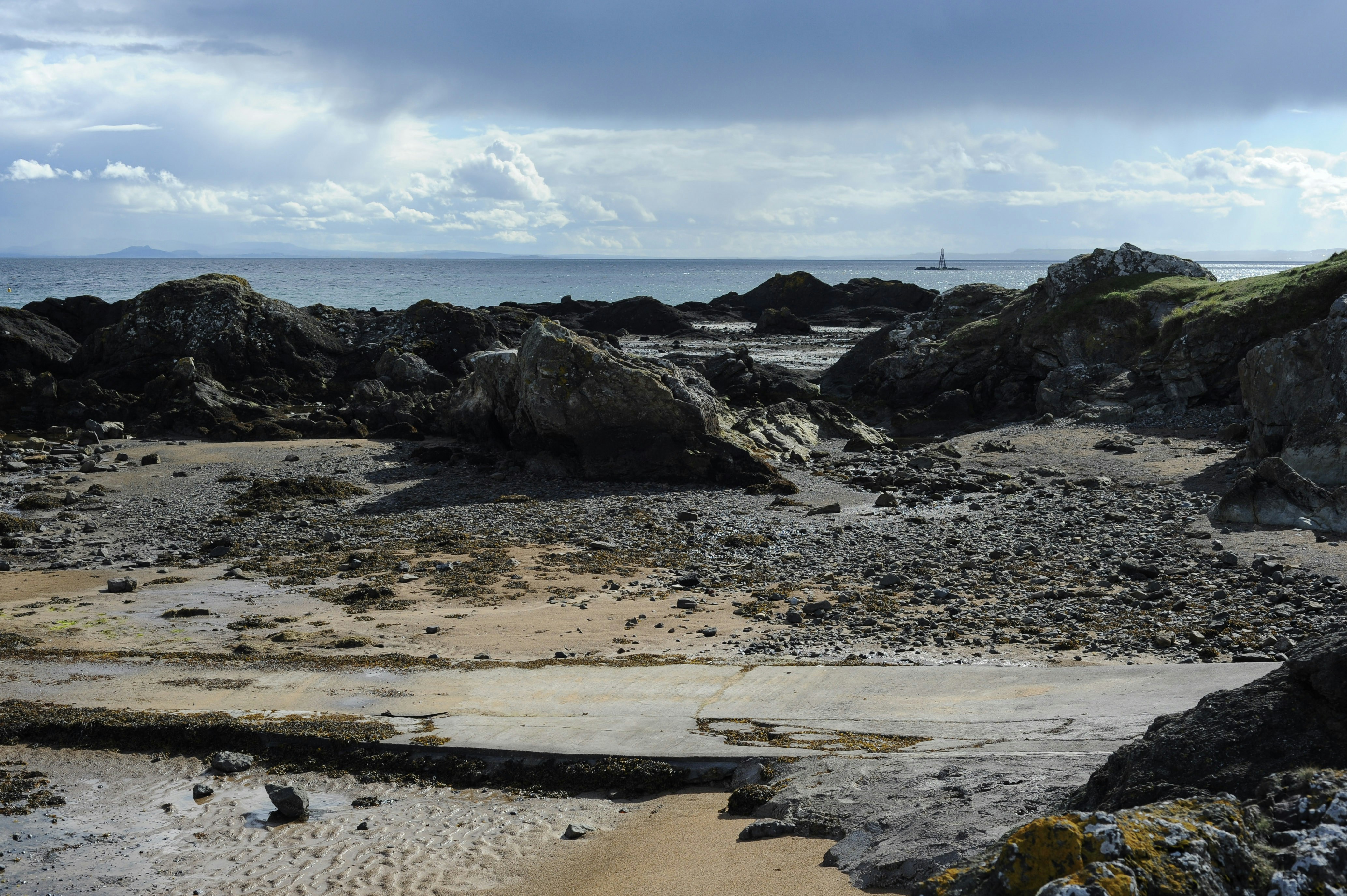 Rocky coastline with sandy beach and cloudy sky