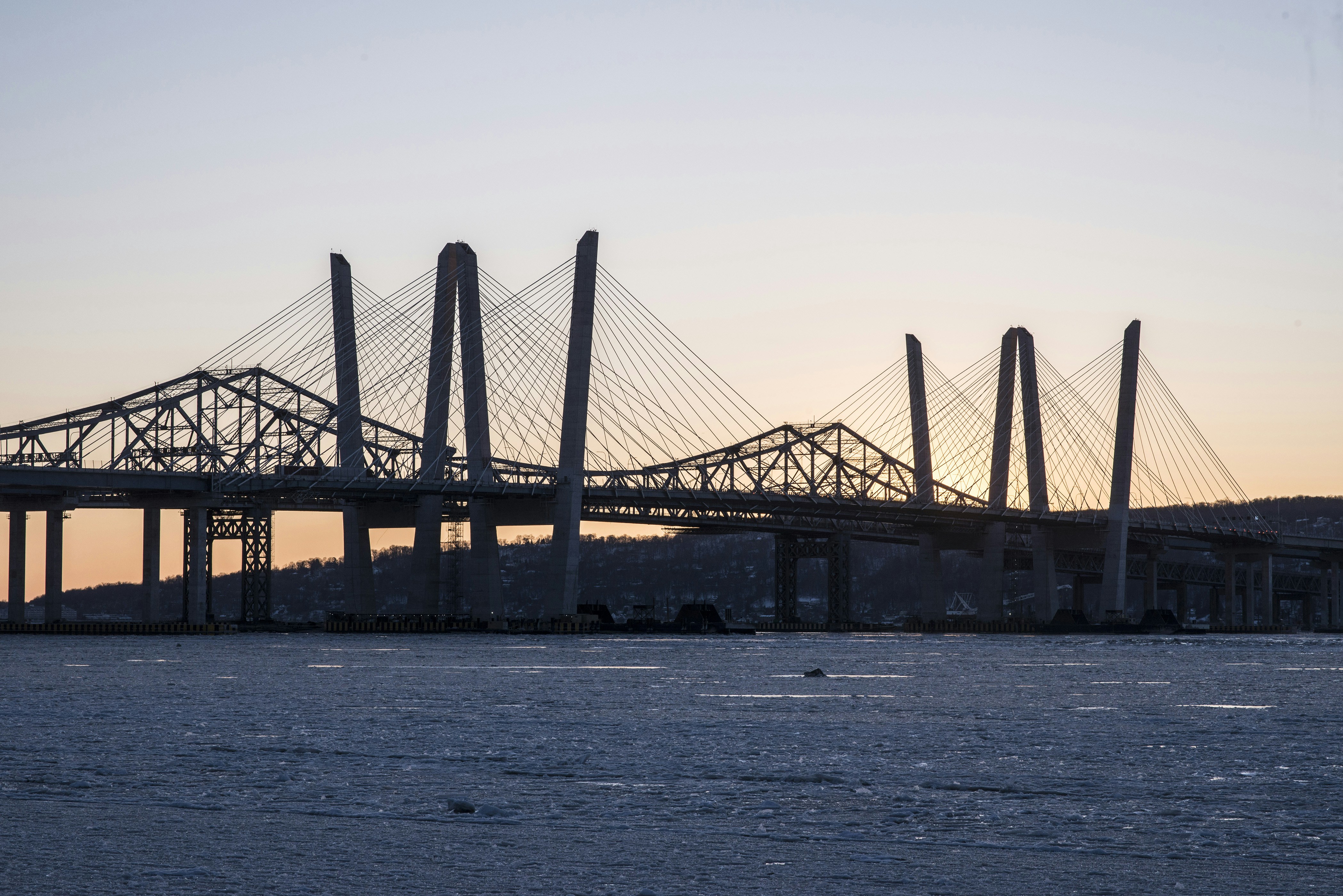 Silhouette of a large bridge over water at sunset
