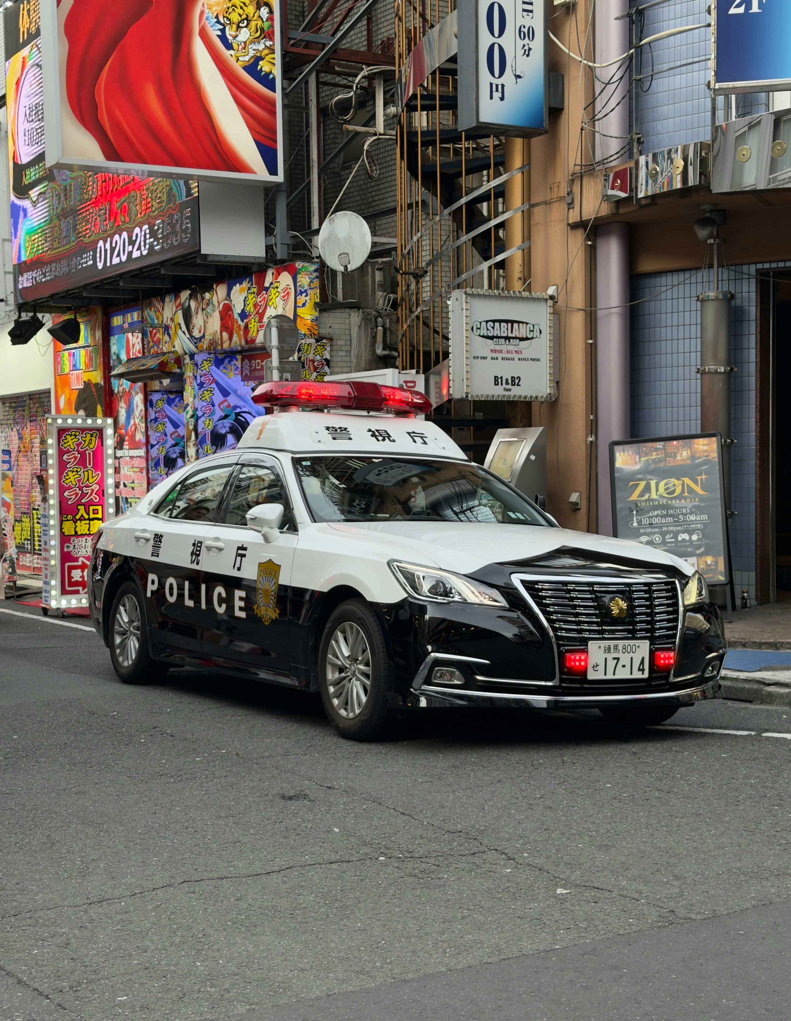 Une voiture de police japonaise garée dans une rue animée de la ville.