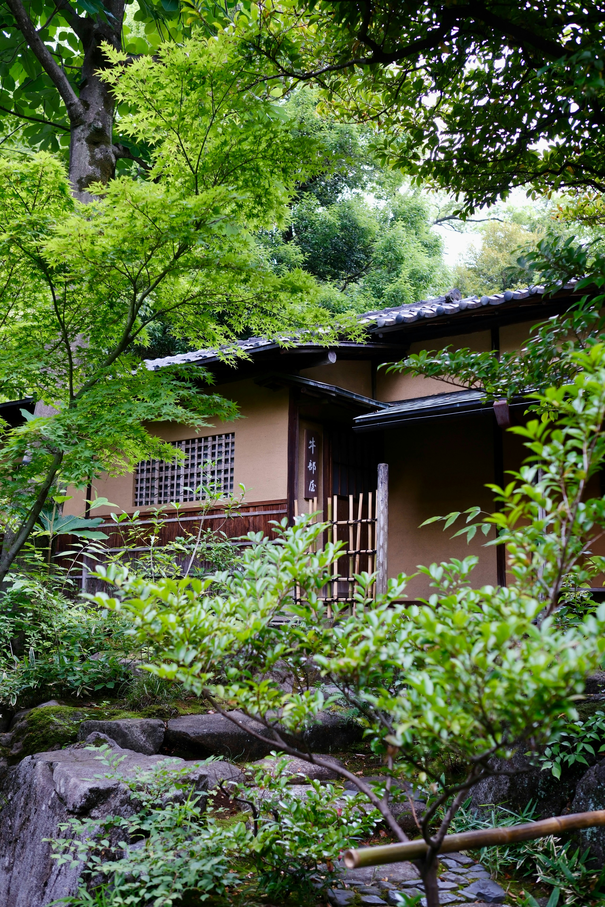 Maison japonaise traditionnelle nichée parmi des arbres verts et des rochers.