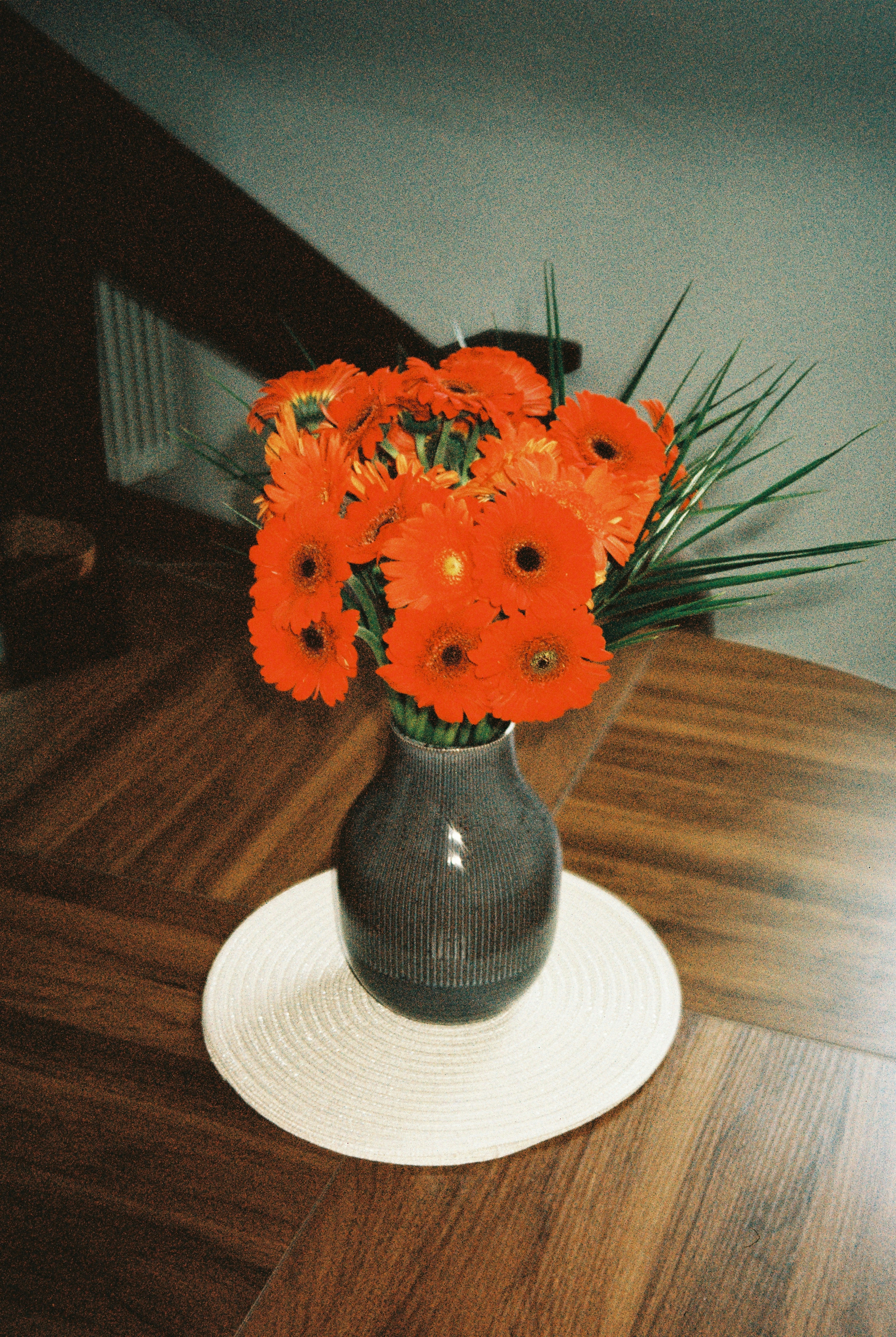 A vase of vibrant orange flowers on a wooden table.
