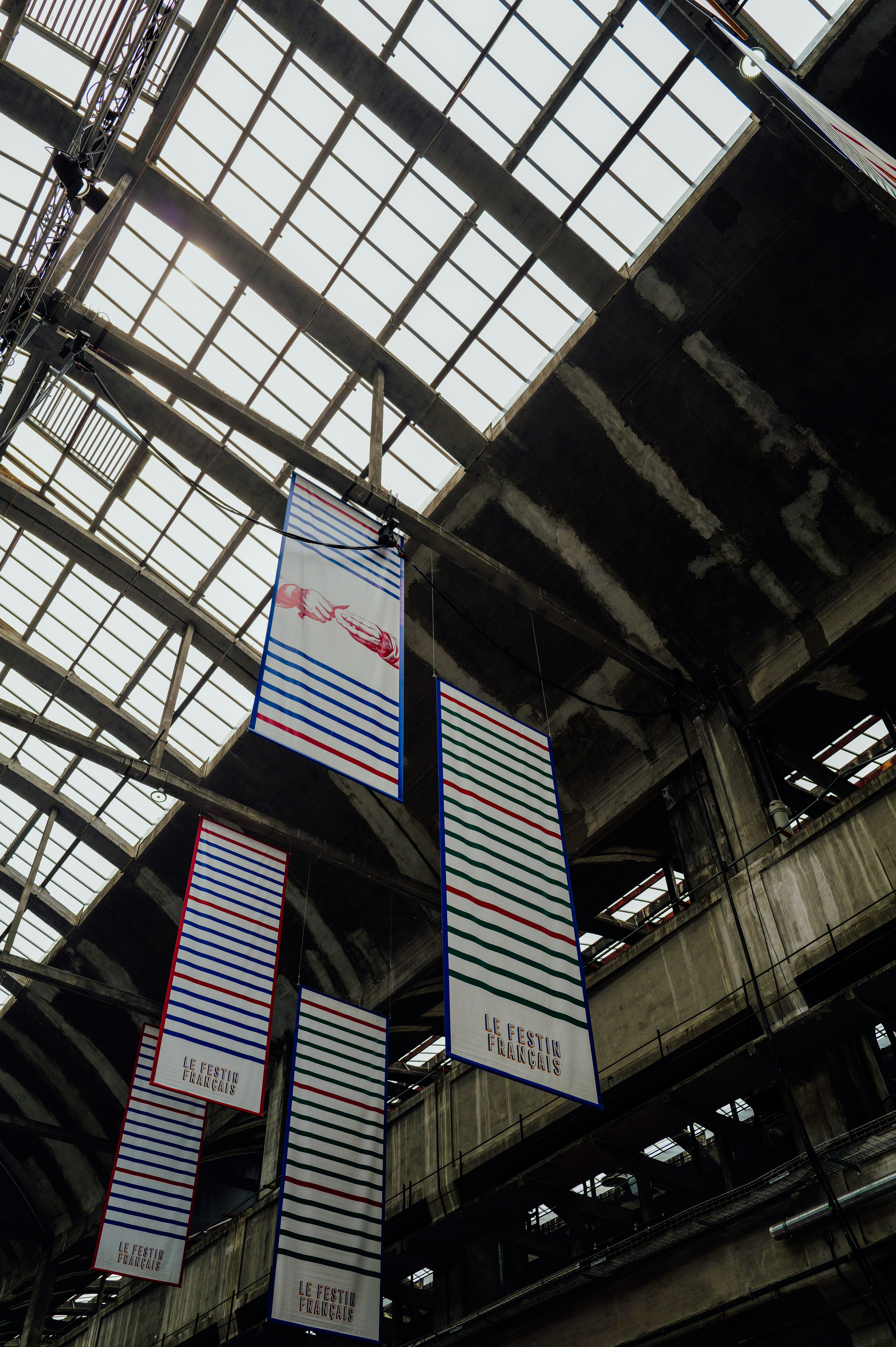 Striscioni pendono da un soffitto industriale alto con lucernari.