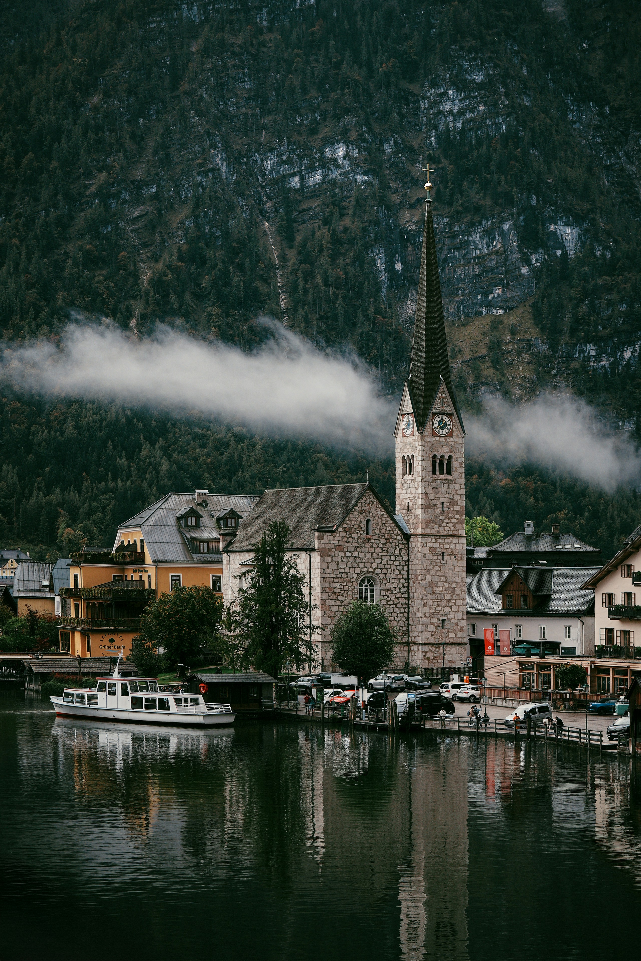 Historic church and village reflected in lake with misty mountains