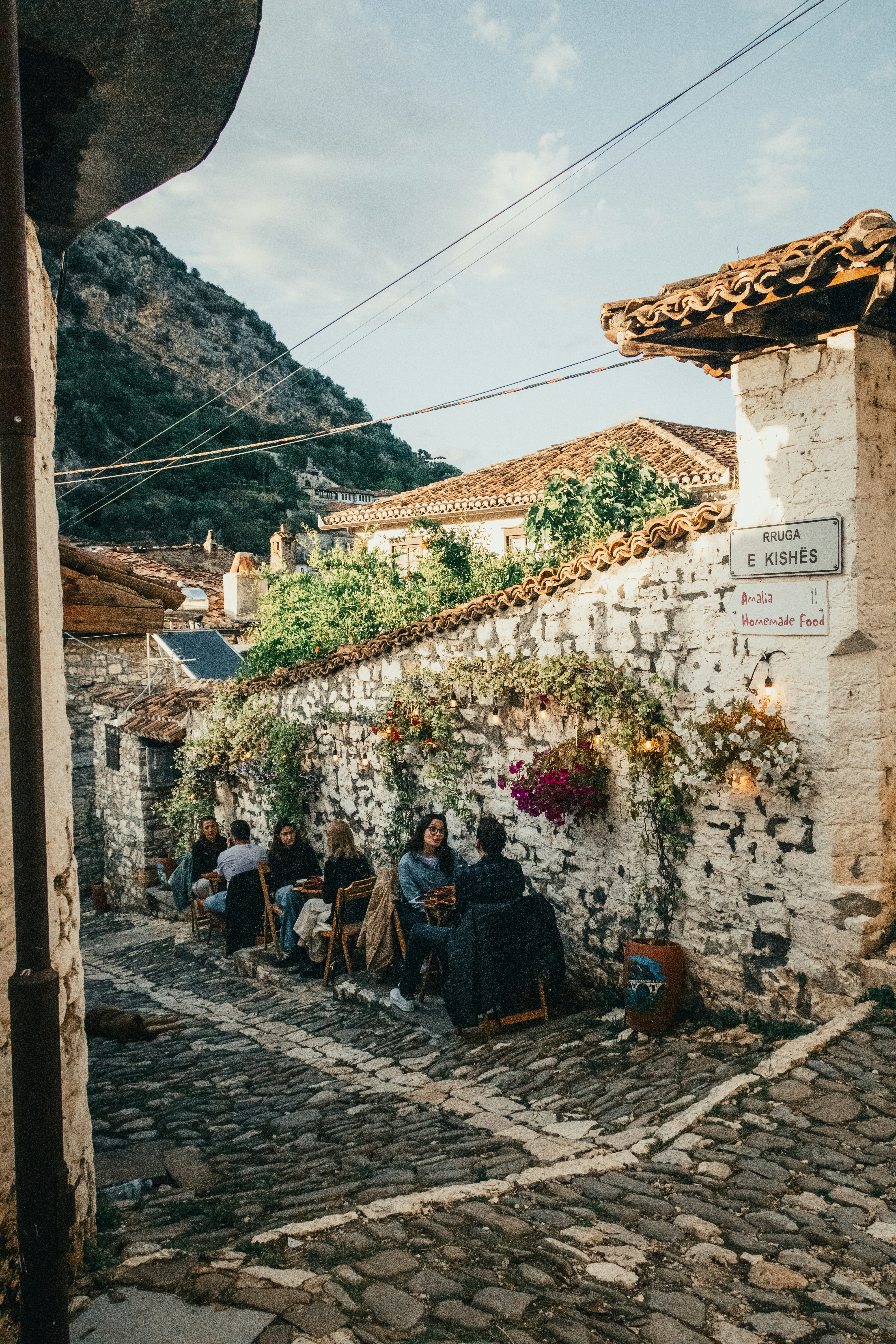 People gather on a quaint, cobbled street with historic buildings