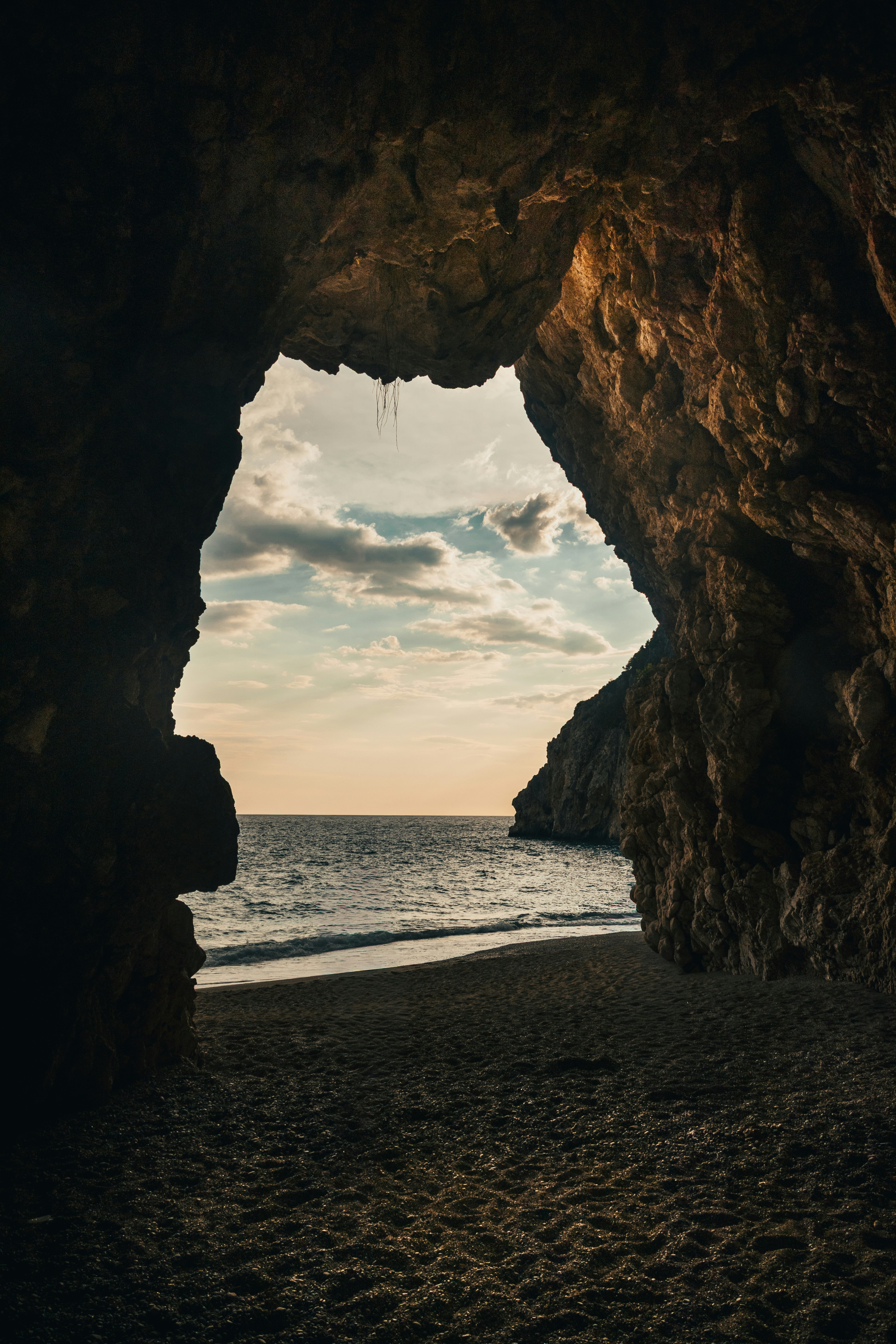 Cave entrance framing a serene beach and ocean