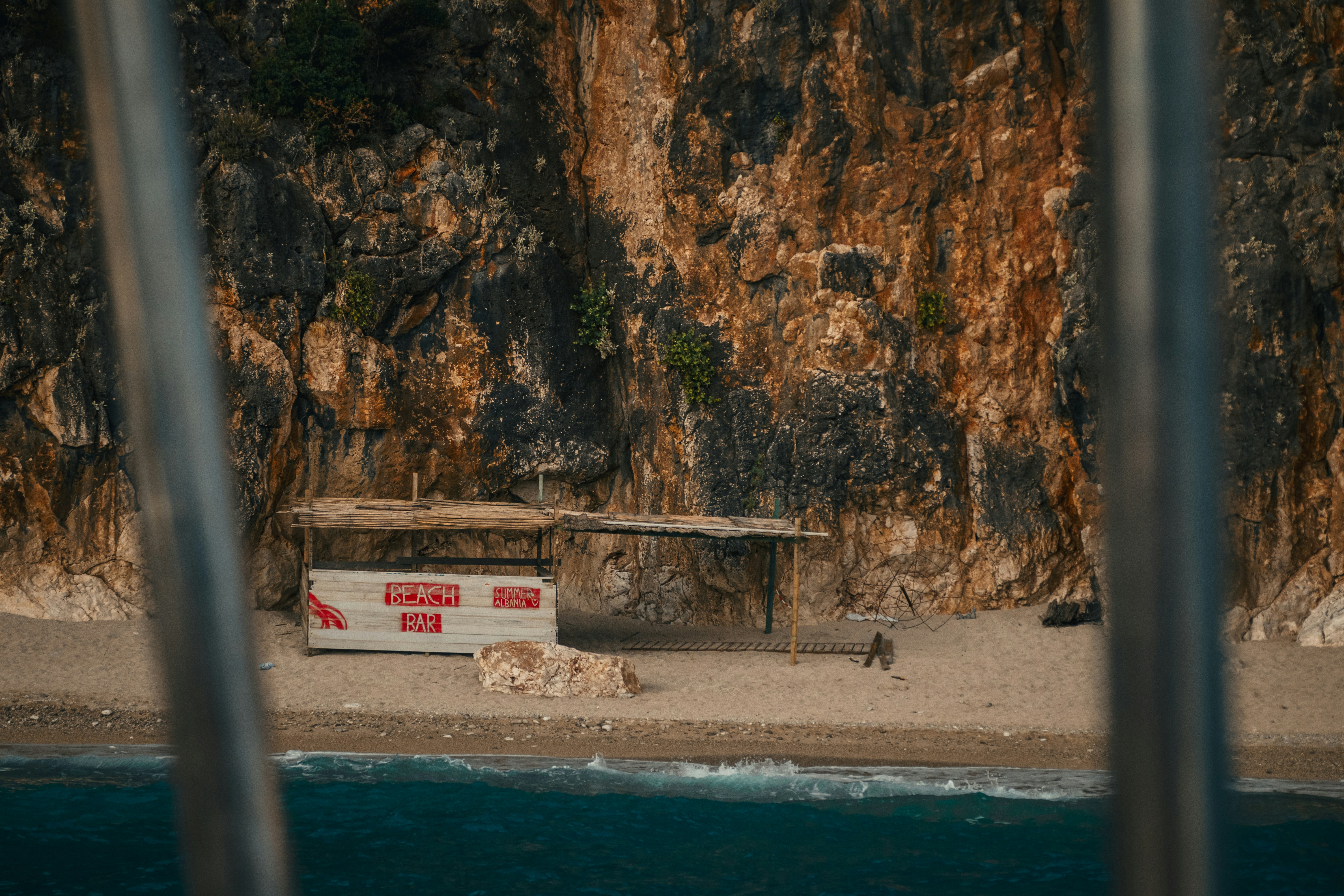 Beach shack nestled under a rocky cliff by the ocean