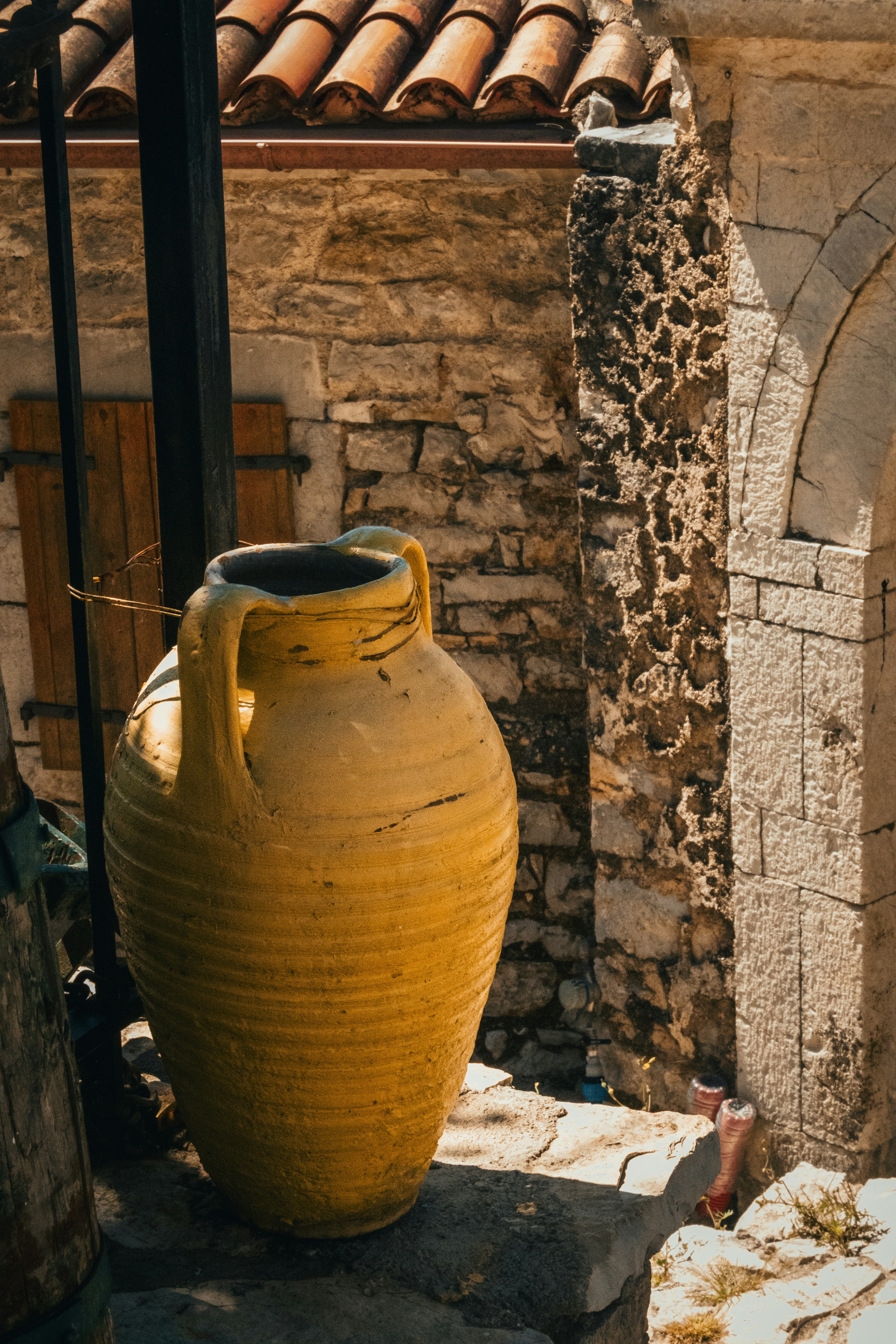 Rustic yellow amphora next to an ancient stone building