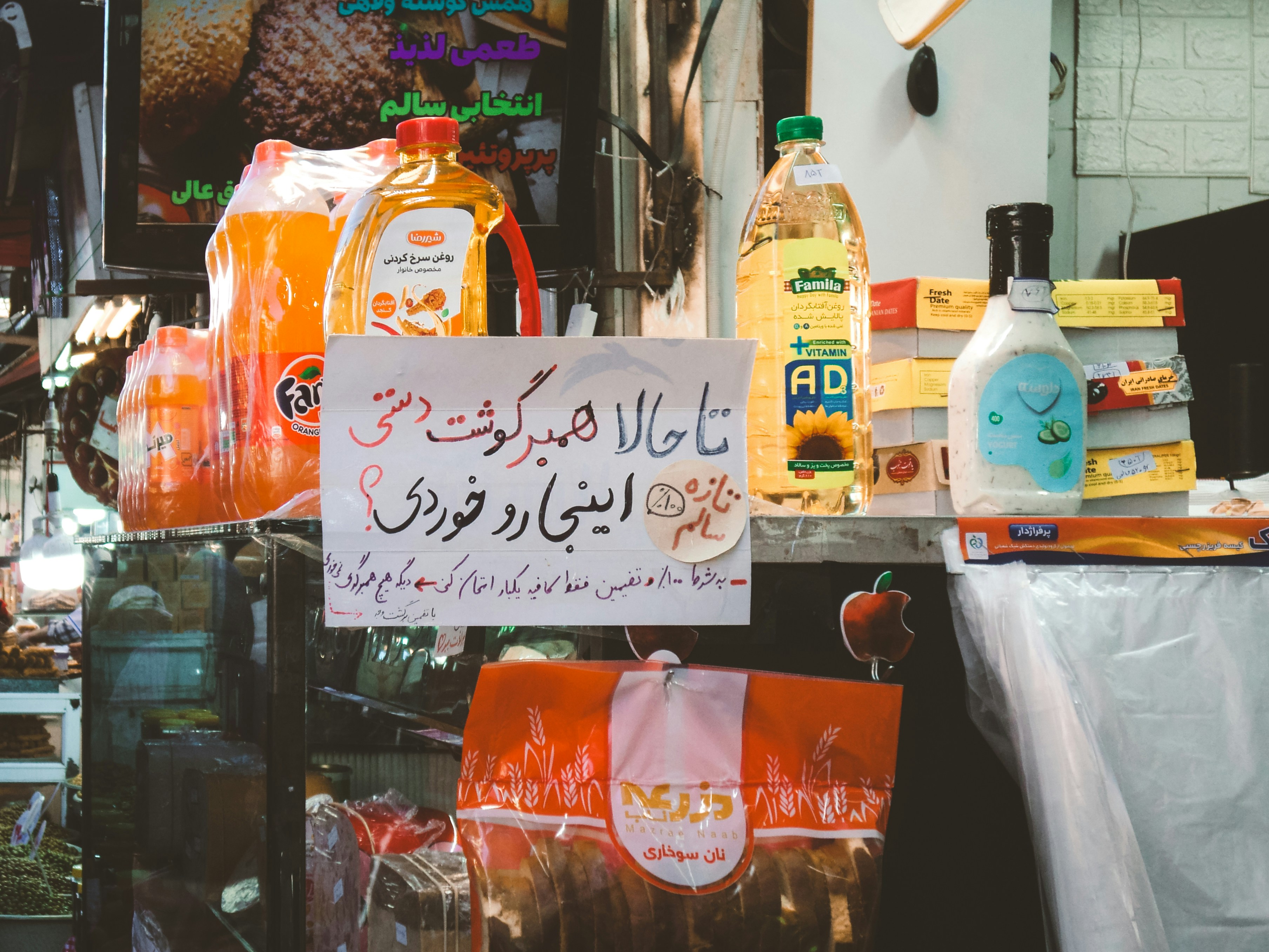 Warung pasar yang memajang produk makanan dengan tanda farsi.