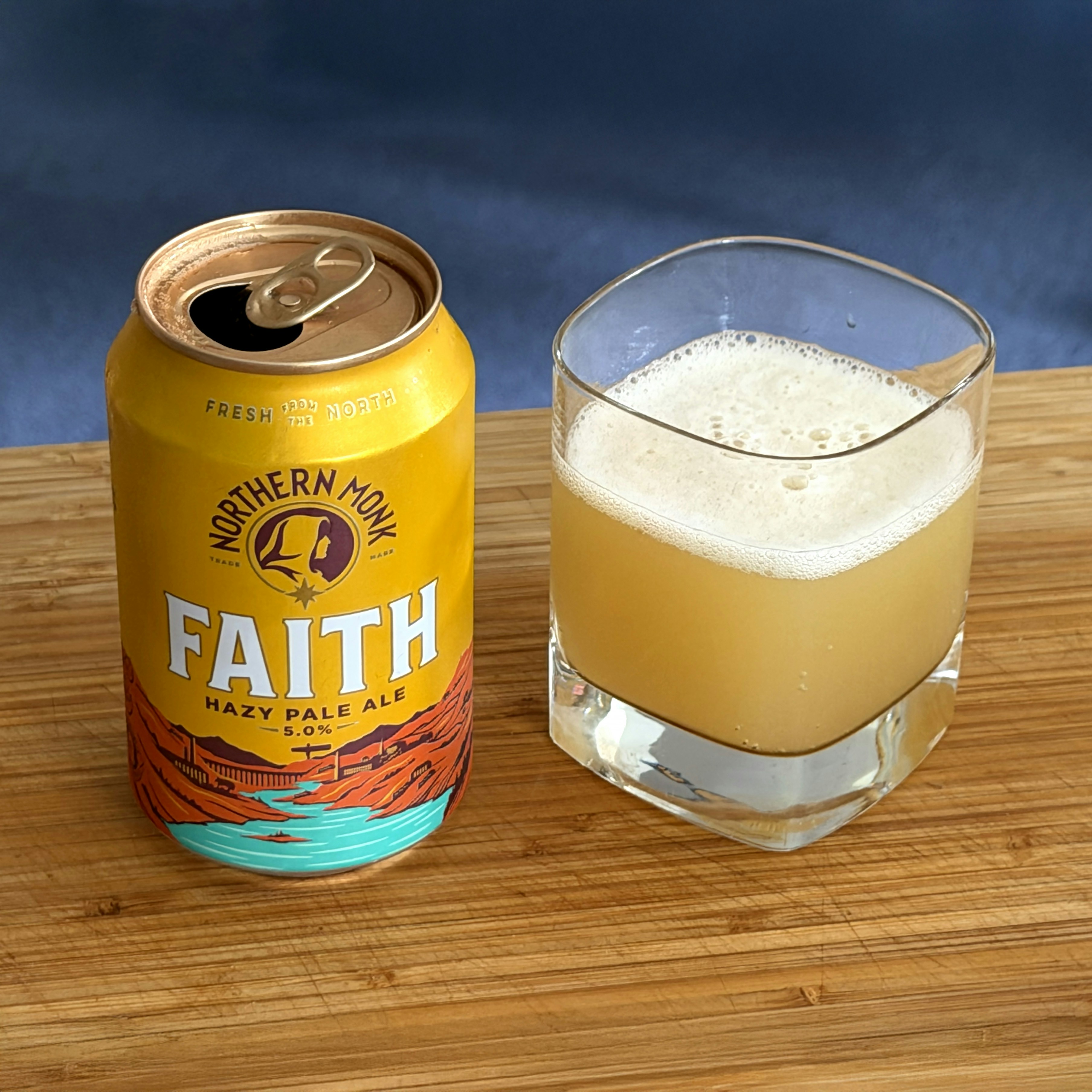 Eine offene Dose Northern Monk Faith Bier neben einem Glas.
