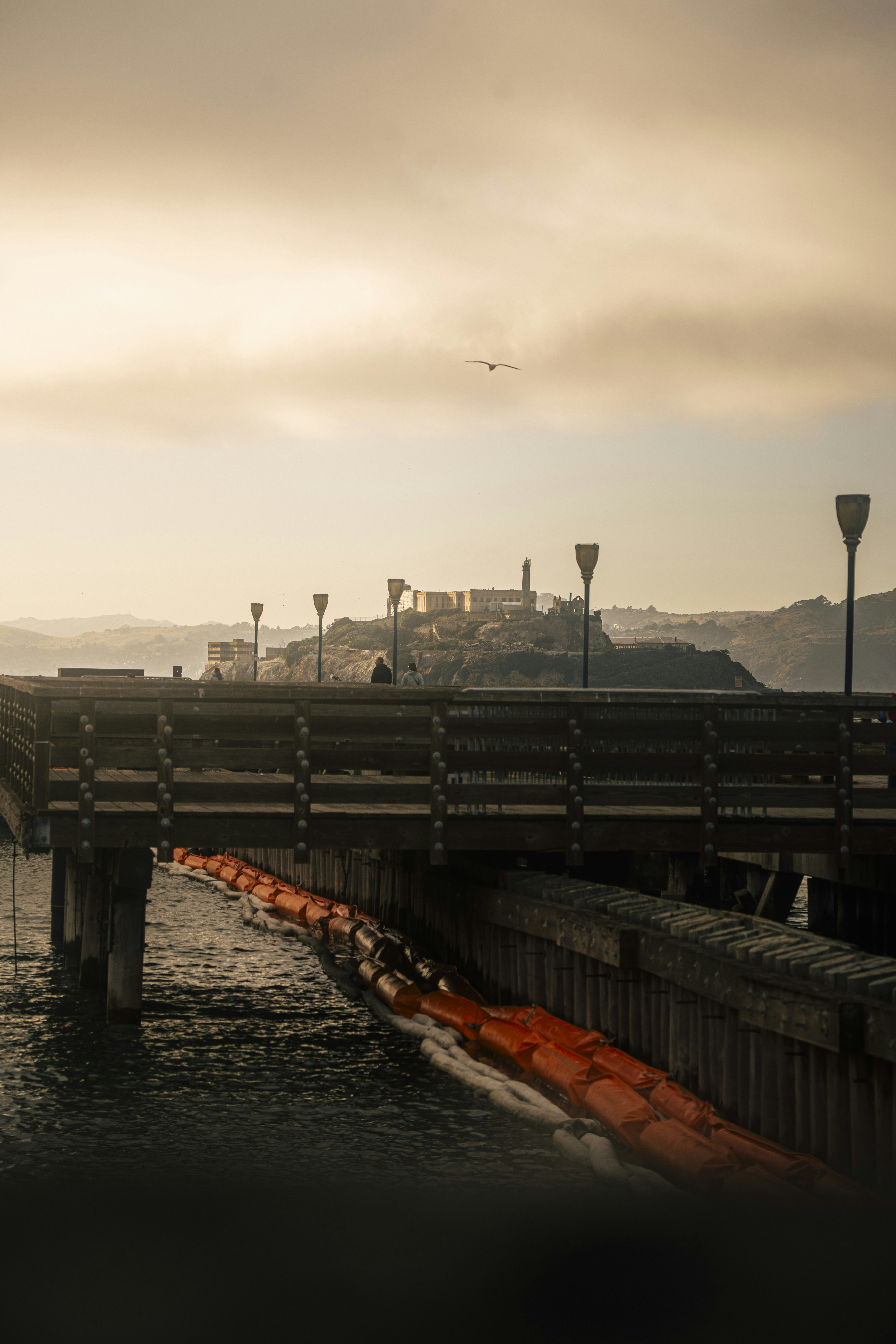 Muelle de madera que conduce a la isla de Alcatraz bajo un cielo brumoso